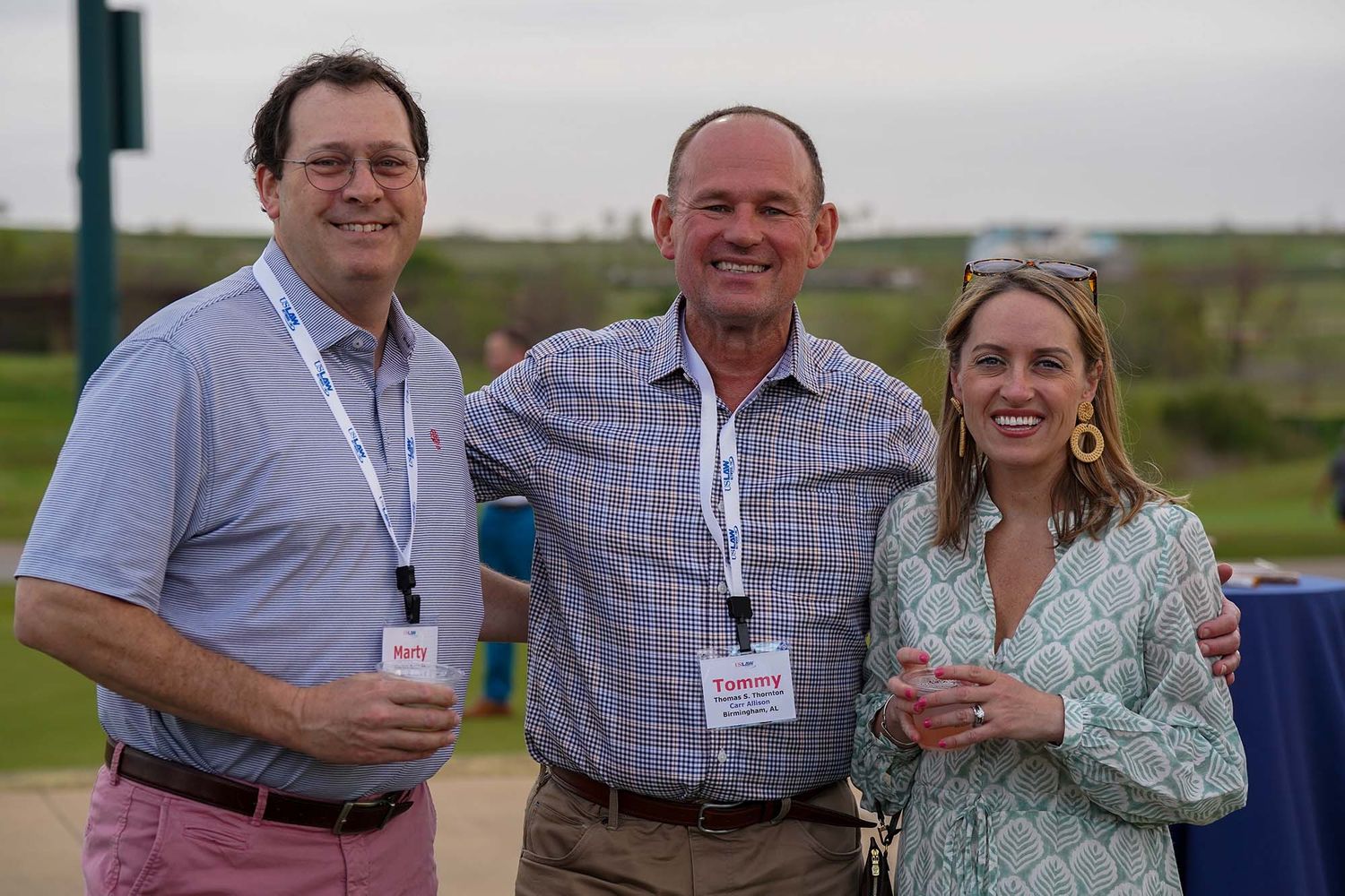 Group of conference attendees networking outdoors with name badges visible.