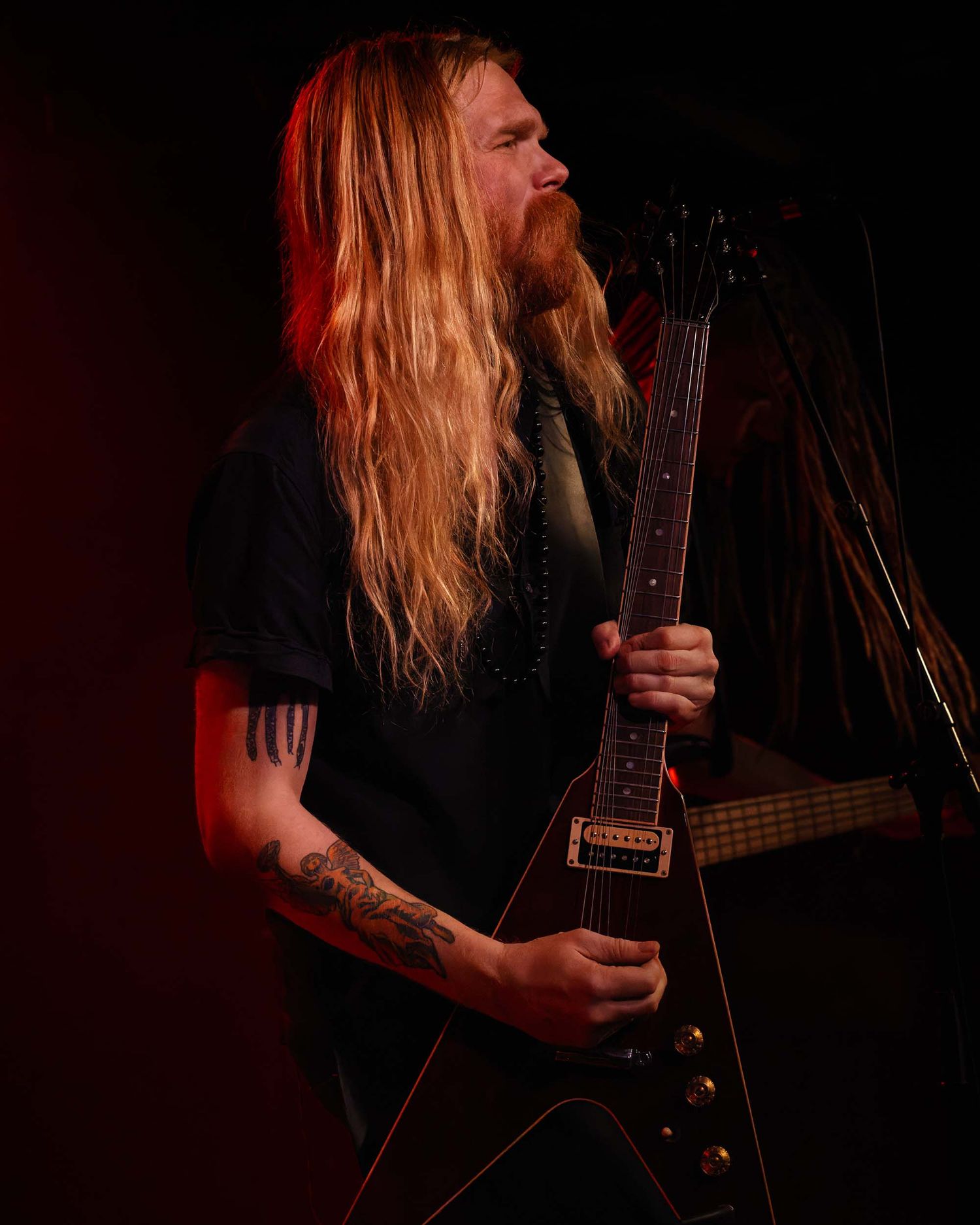 Dramatic portrait of a musician playing guitar in dark moody lighting.