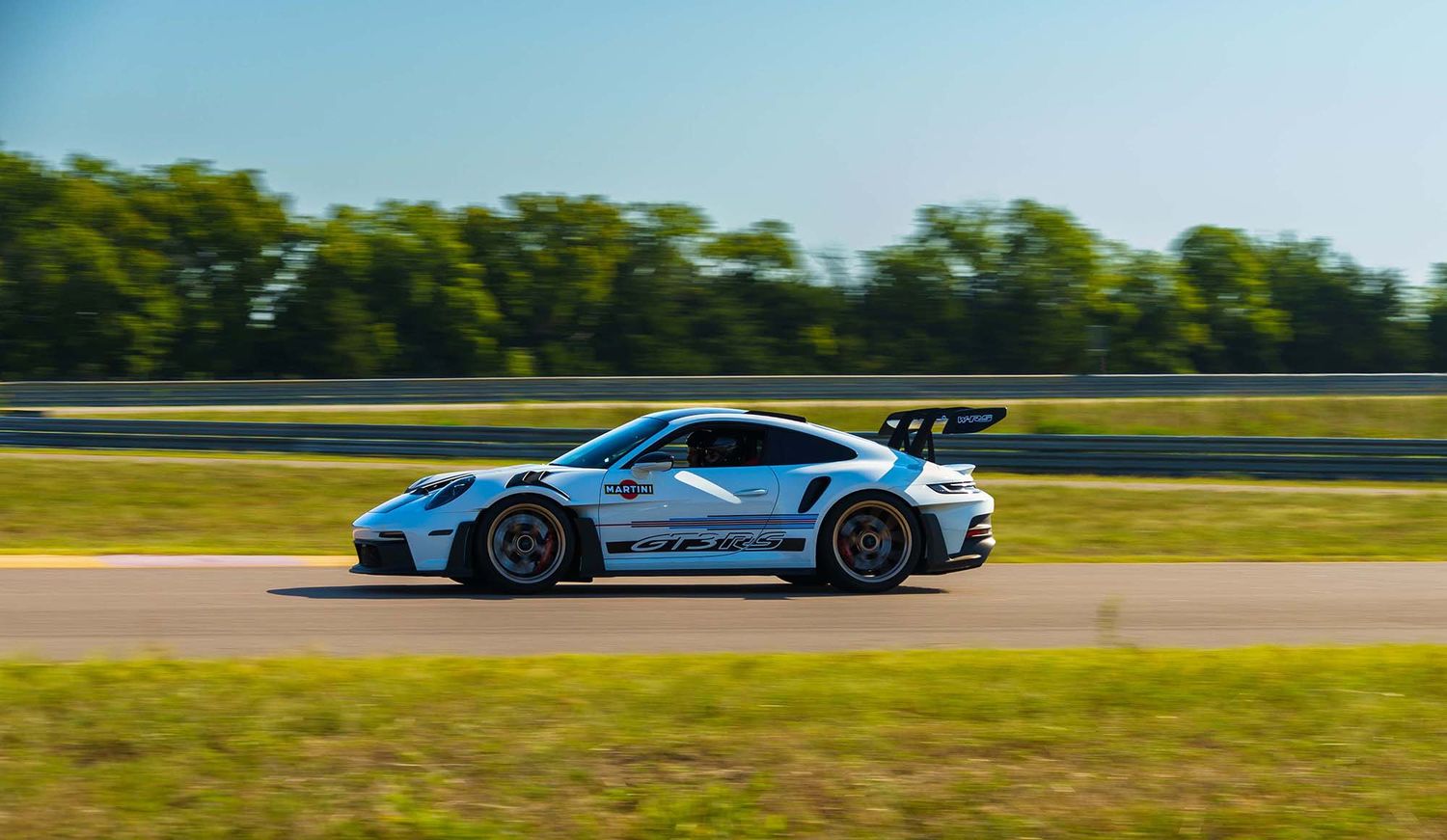 Performance cars speeding along a professional racing circuit on a clear summer day.