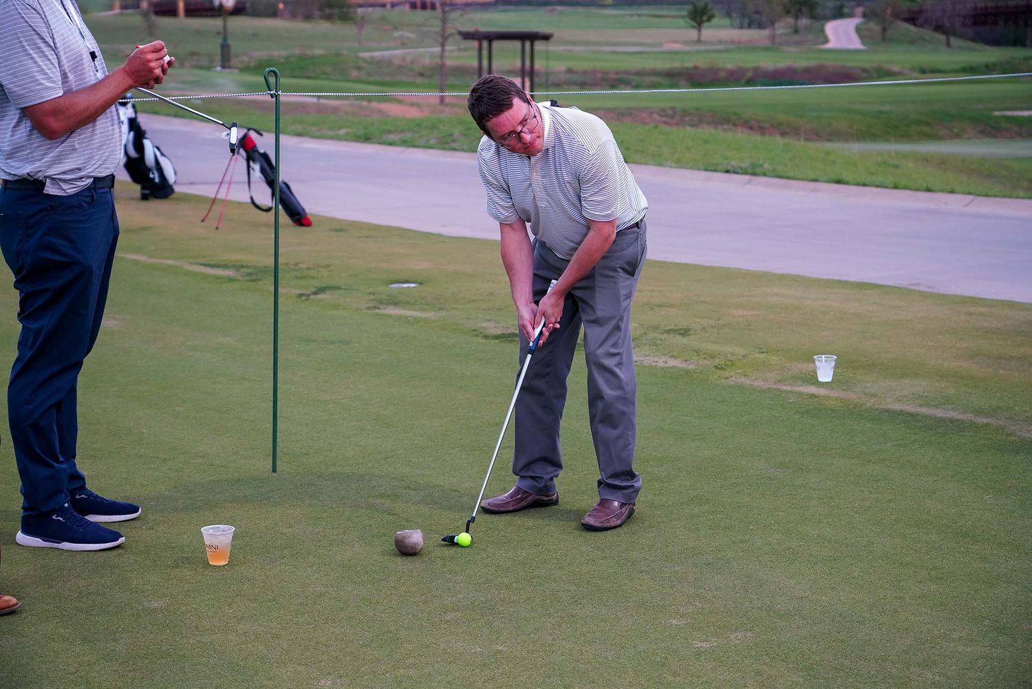 People playing miniature golf on a putting green during a corporate event.