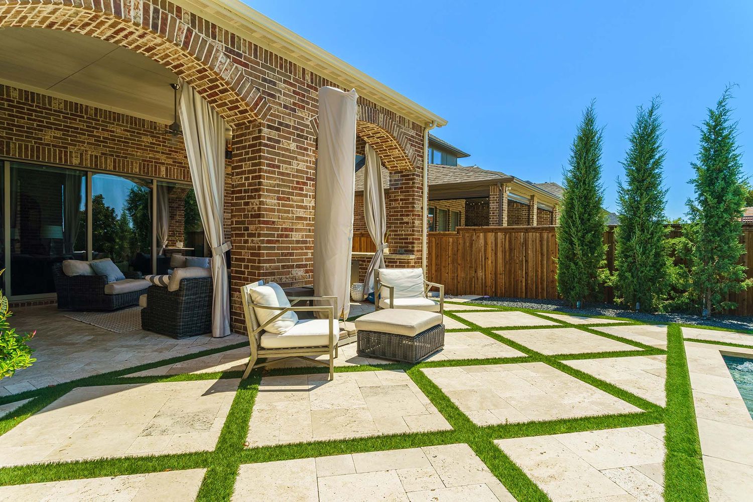Modern backyard patio with white stone pavers and contemporary landscaping design.