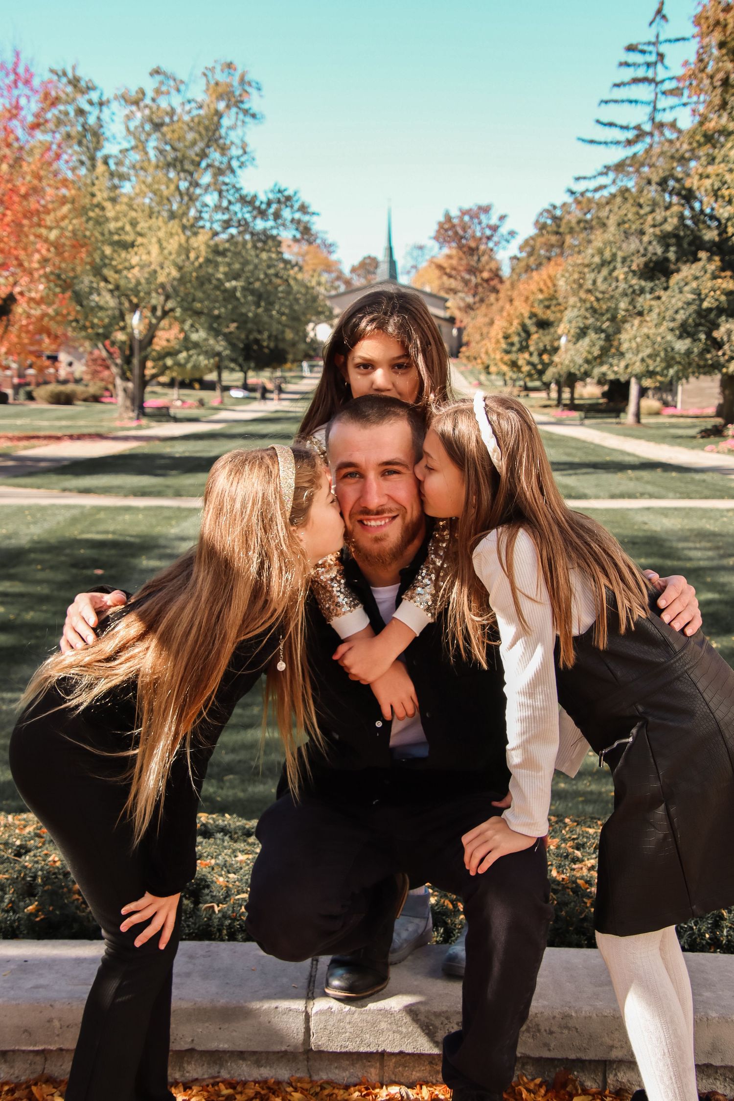 Daughters give dad a kiss.