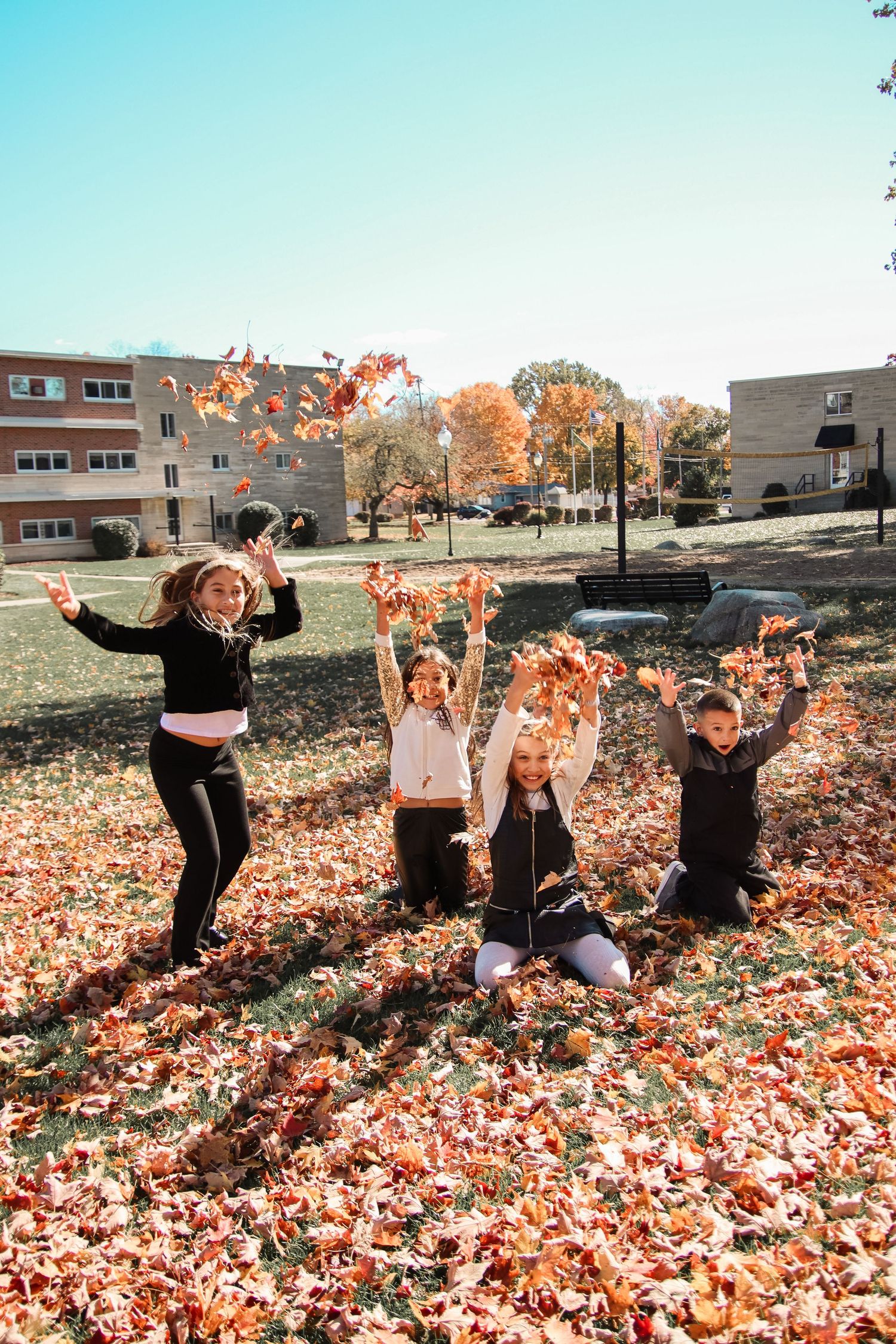 All siblings playing in the leaves.
