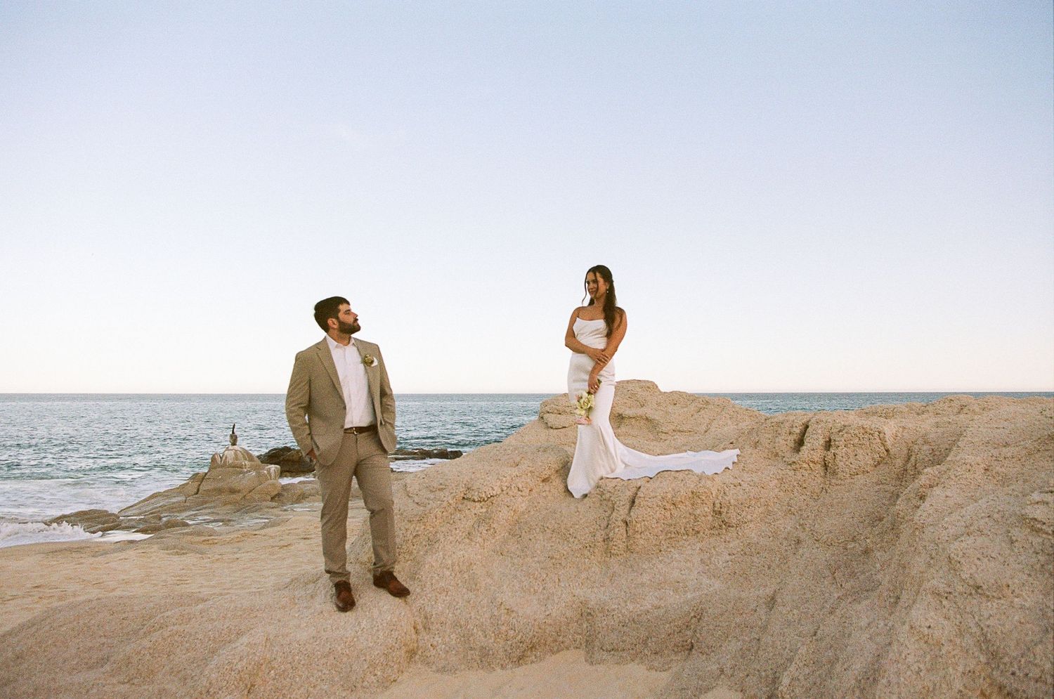 Dramatic portrait of newlyweds on rocky beach in San José del Cabo.