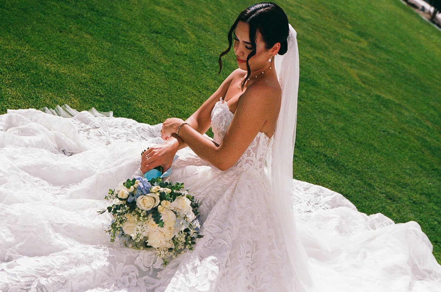 Editorial up close bridal portrait of bride sitting in grass with bouquet.