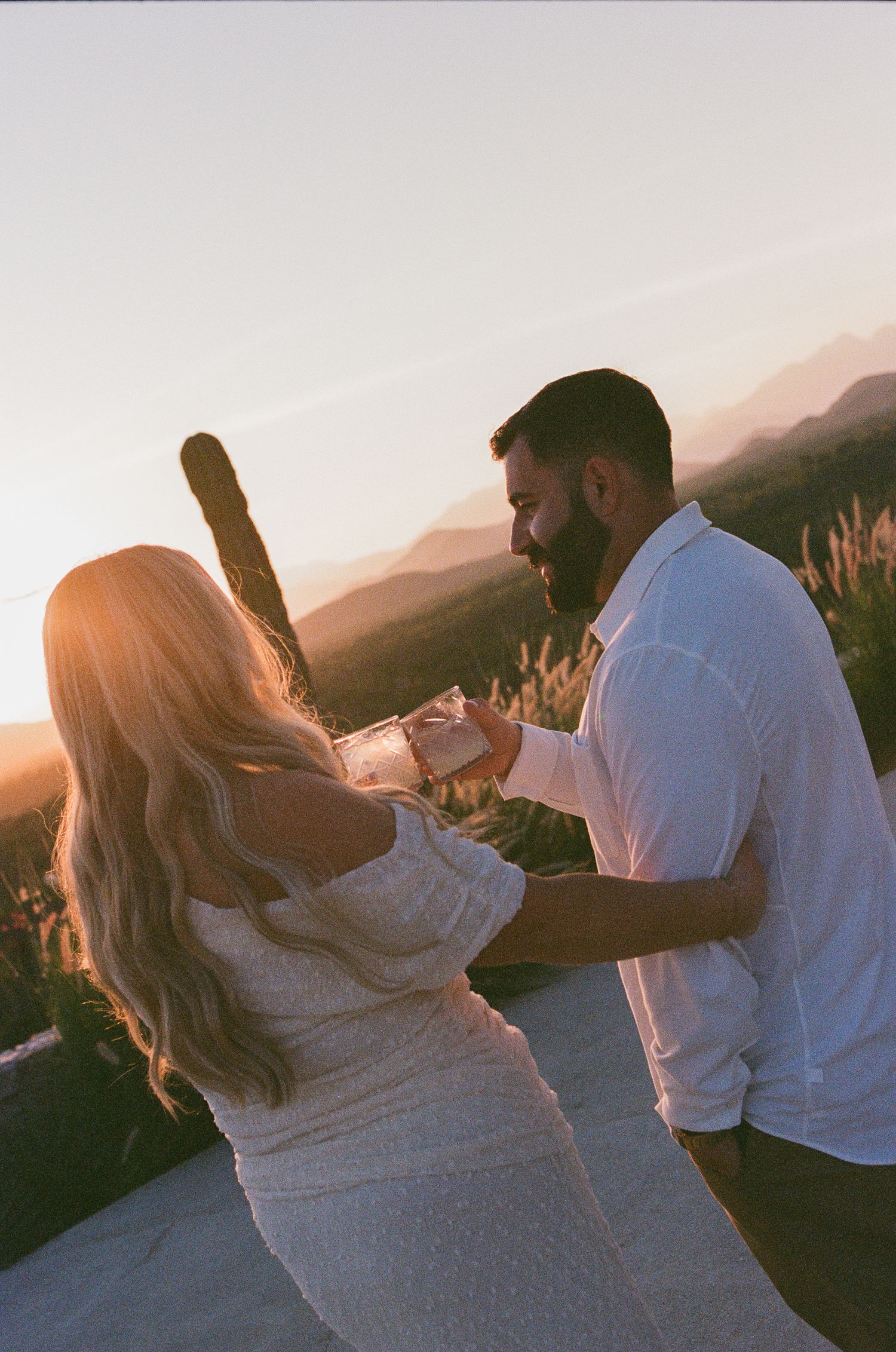 Couple holding hands at golden hour sunset with mountains and cacti in the background at wedding venue Monte Cardon.