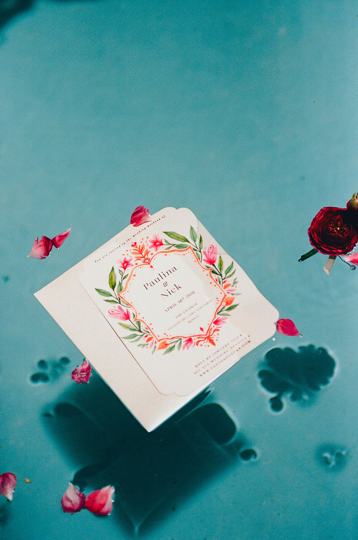 Wedding invitation floating with flowers in pool.