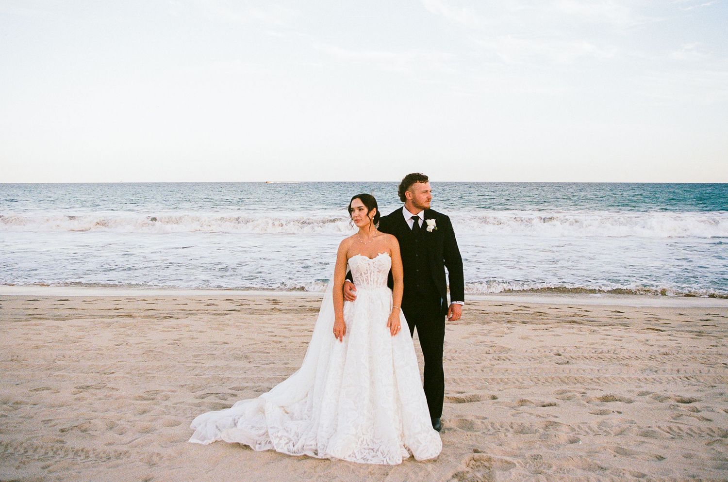 Editorial portrait of newlyweds standing side by side on the beach in San José del Cabo.
