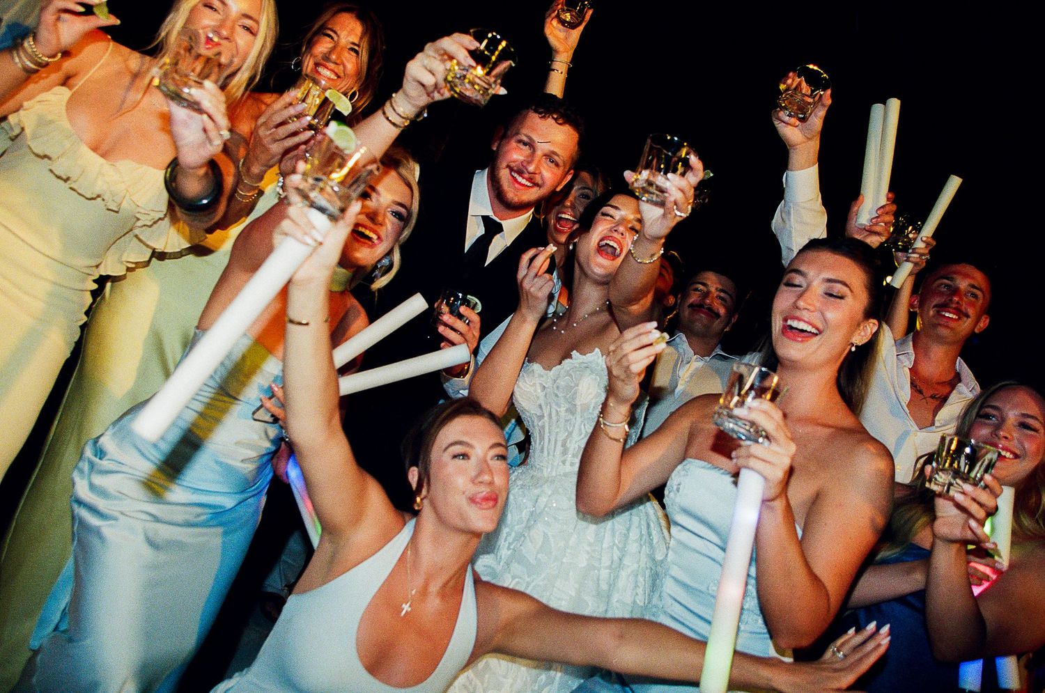 High energy wedding reception with bride and groom and friends cheering.