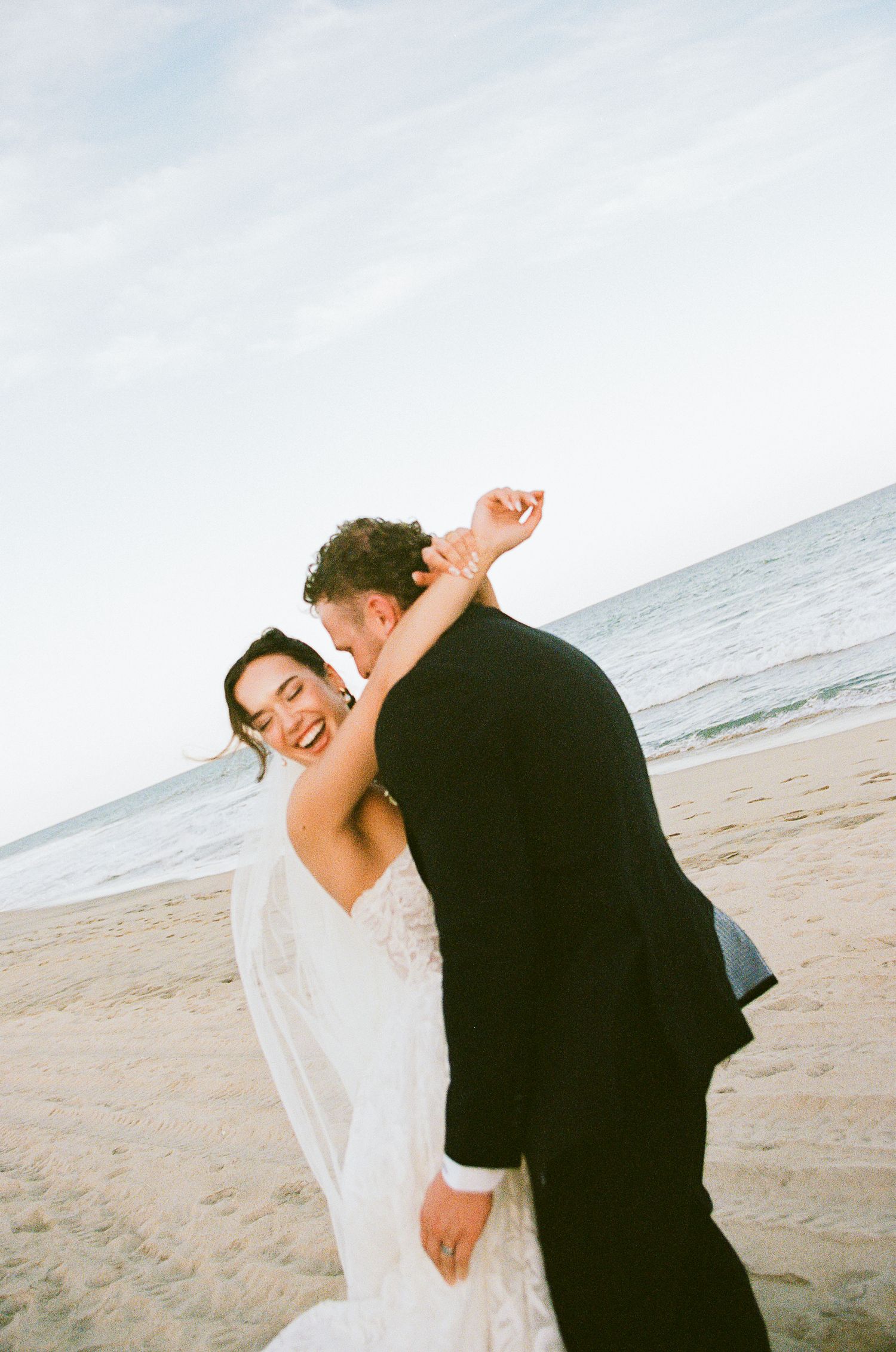 Bride and groom embracing and laughing on the beach in San José del Cabo.