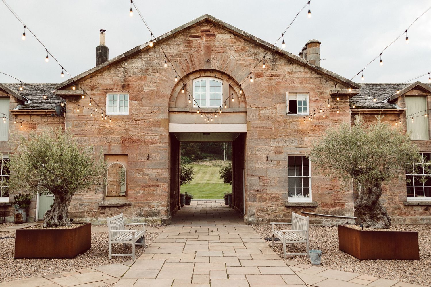 Historic stone courtyard with rustic archways and paved walkway features weathered architectural details and planters.