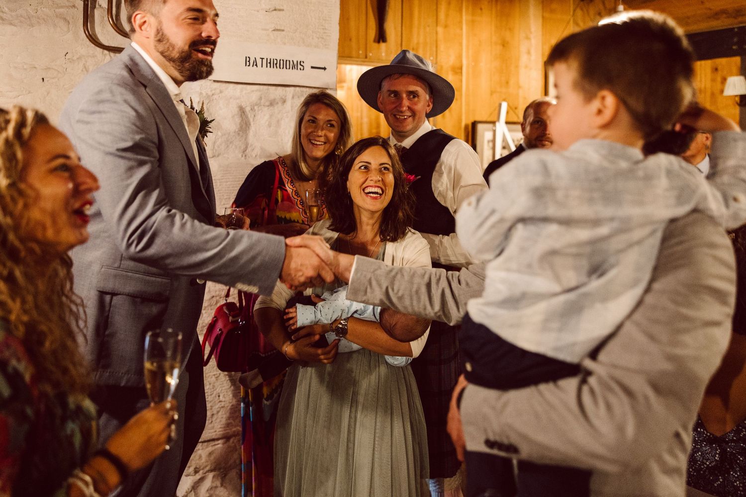 Couples dance together in a warm, rustic venue during a wedding celebration.