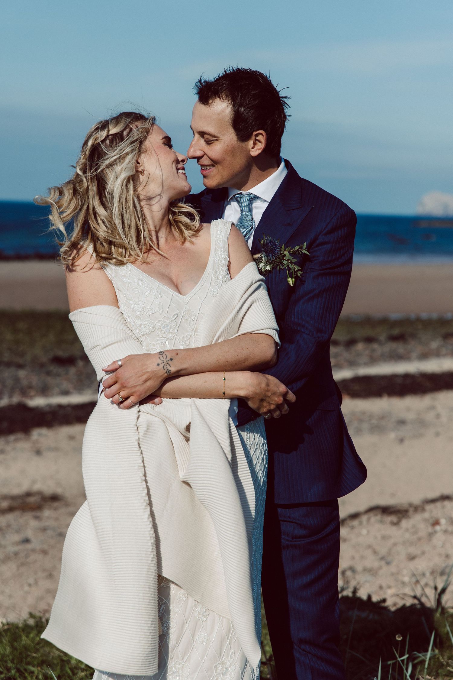 A bride and groom share romantic kisses in a series of intimate beach wedding photos against a coastal backdrop.