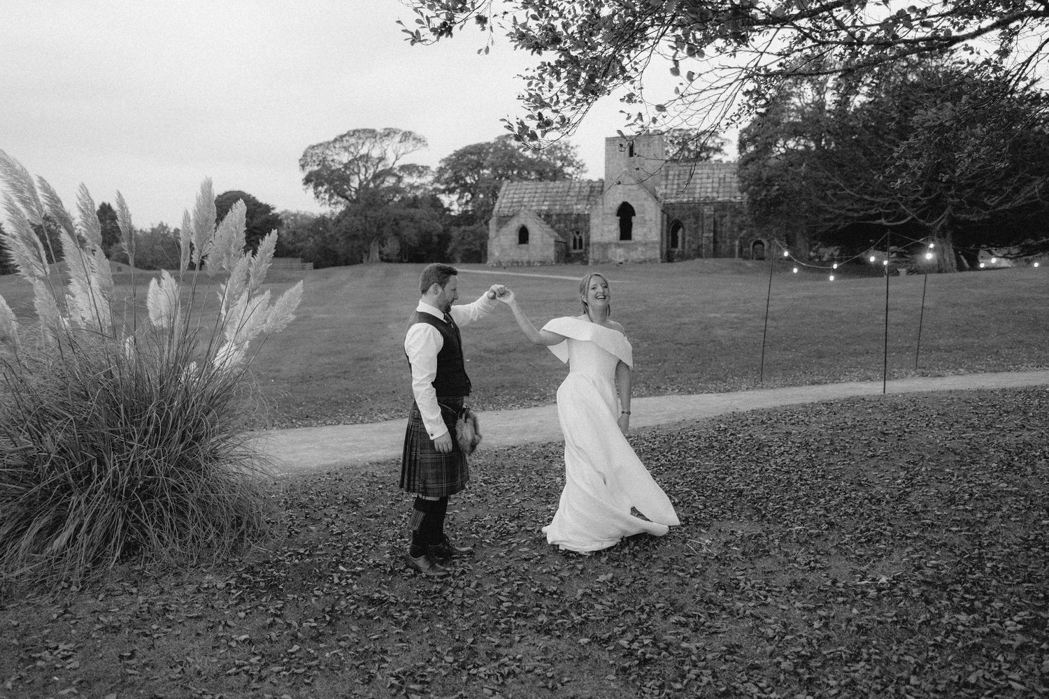 Black and white panoramic sequence showing people running through a field in vintage dress.