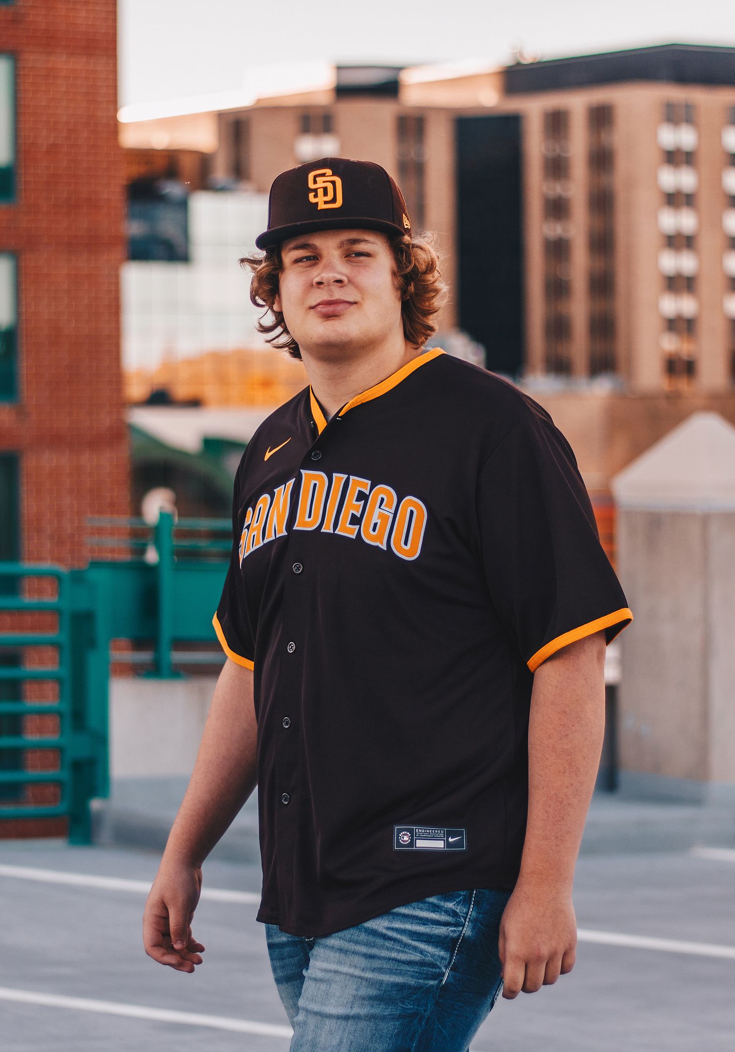 Young man in San Diego Padres baseball jersey and cap in urban setting.