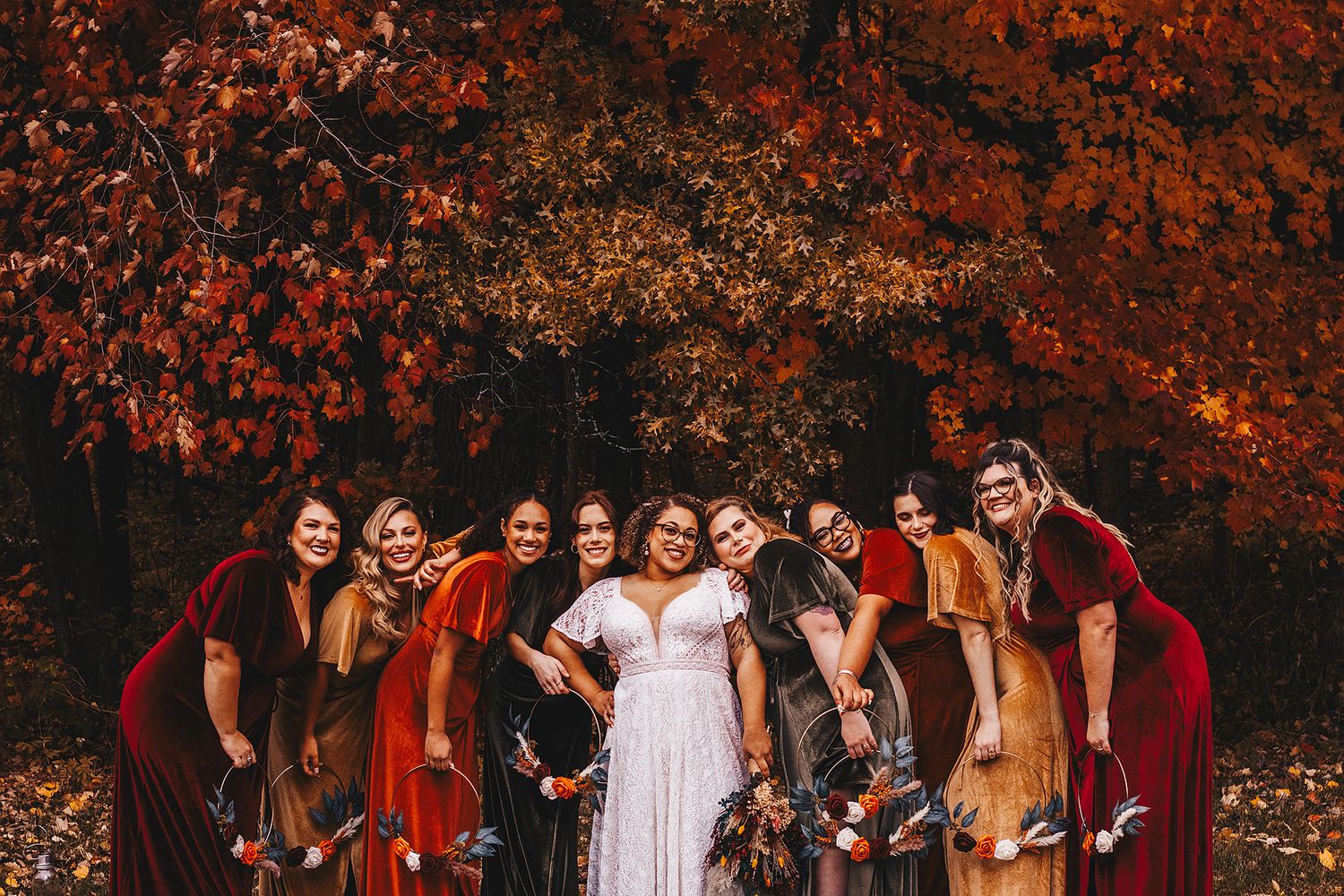 Boho lace wedding dress hanging on geometric hexagonal arch decorated with fall flowers and macrame fringe.