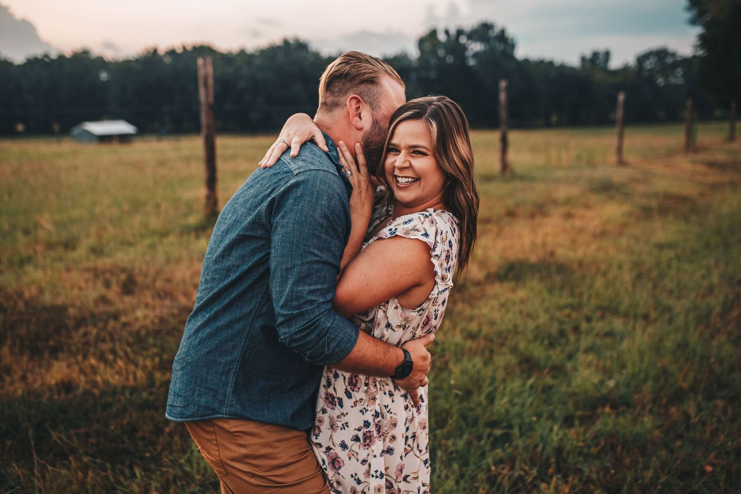 Happy couple embracing in golden field at sunset.