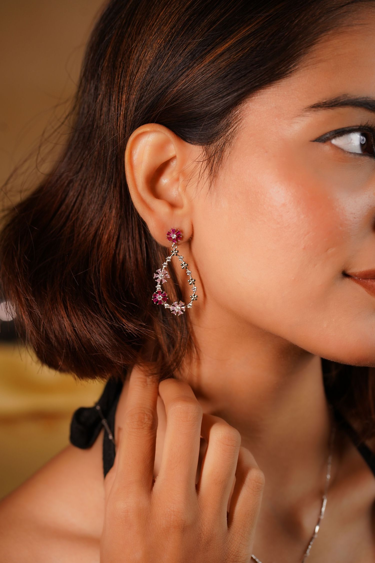 Woman wearing elegant pink gemstone and crystal drop earrings, showcasing delicate jewelry design.