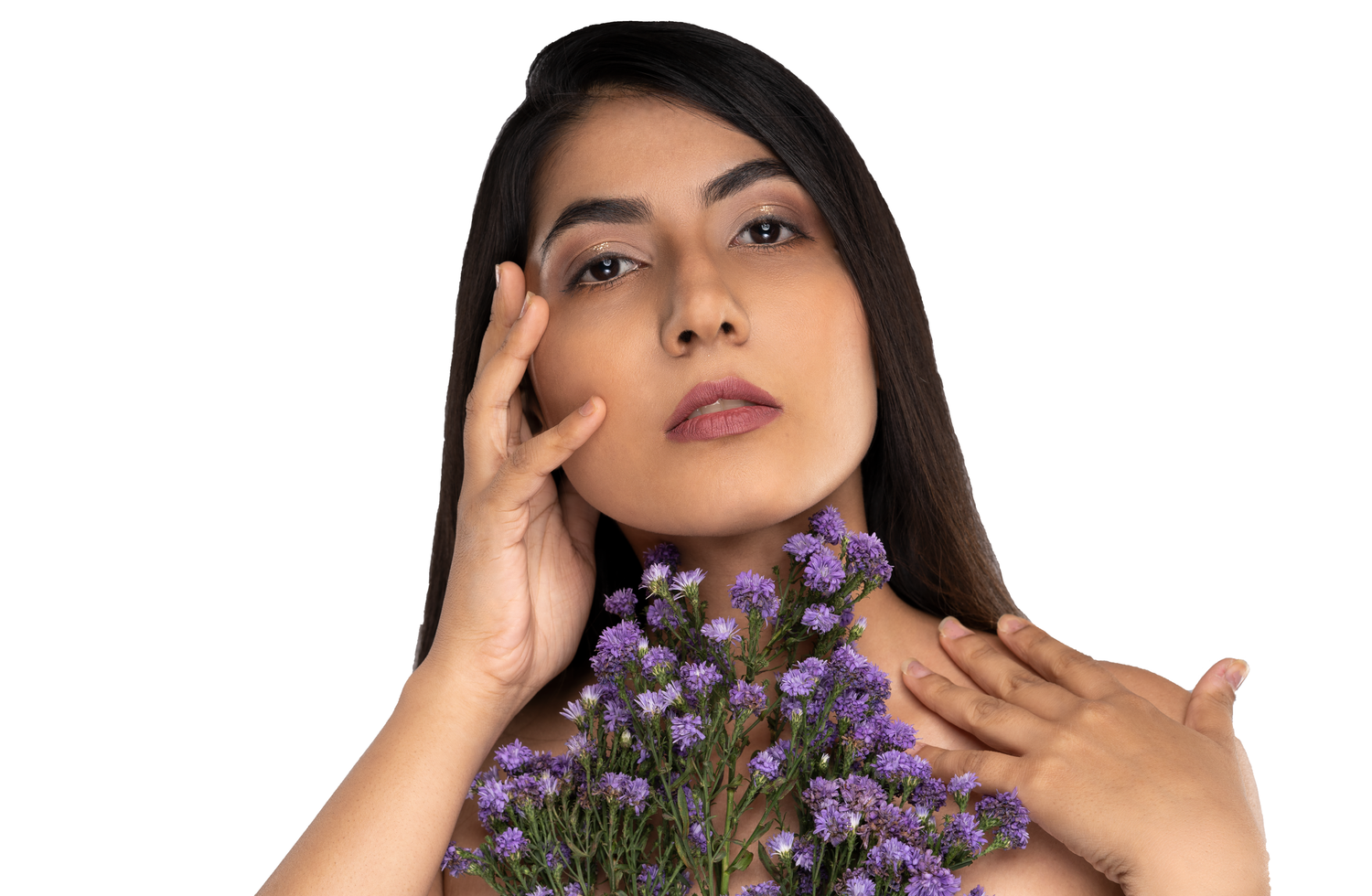 Young woman with long dark hair holding purple wildflowers near her face against a white background.