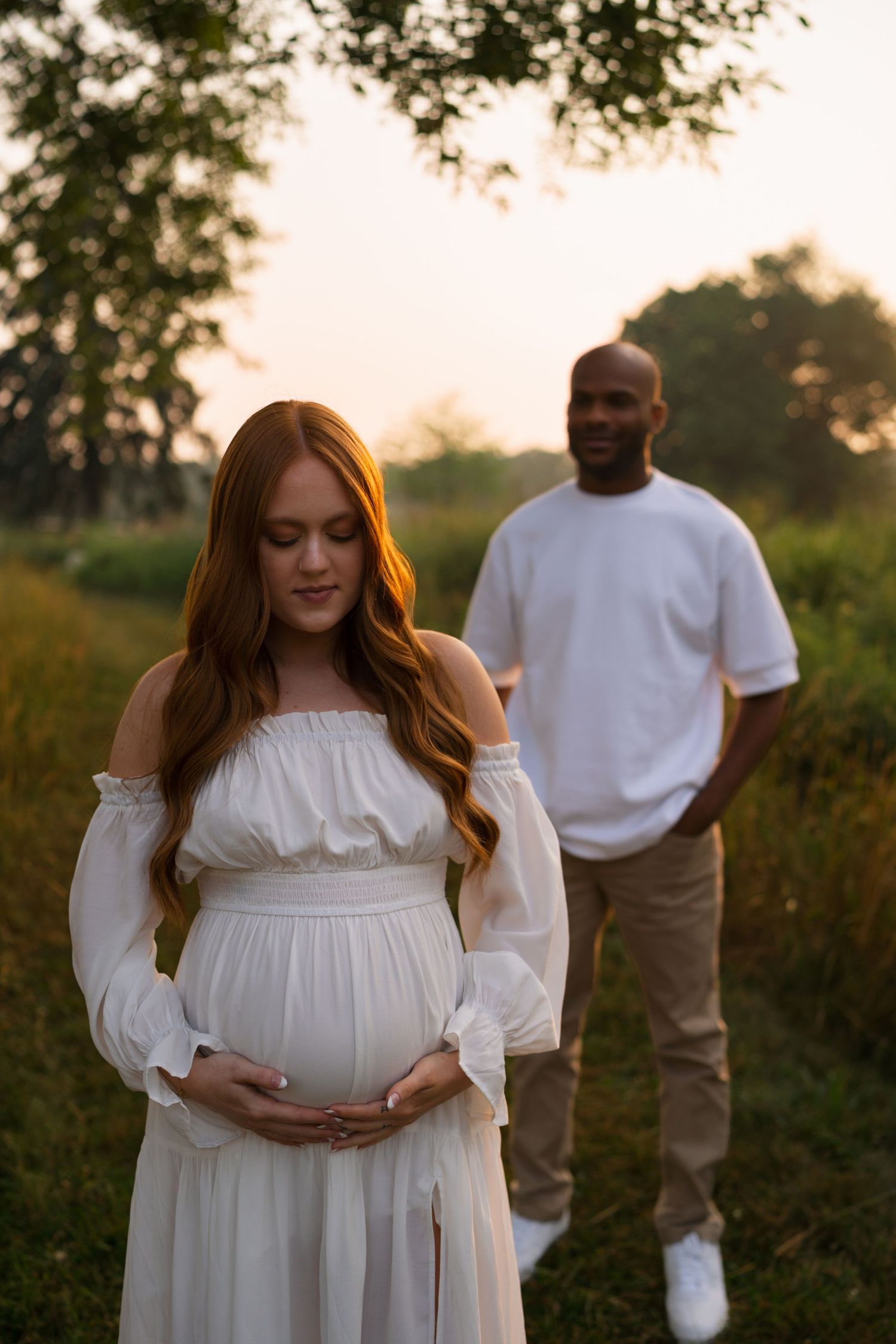 Expectant parents sharing a joyful moment in the prairie.