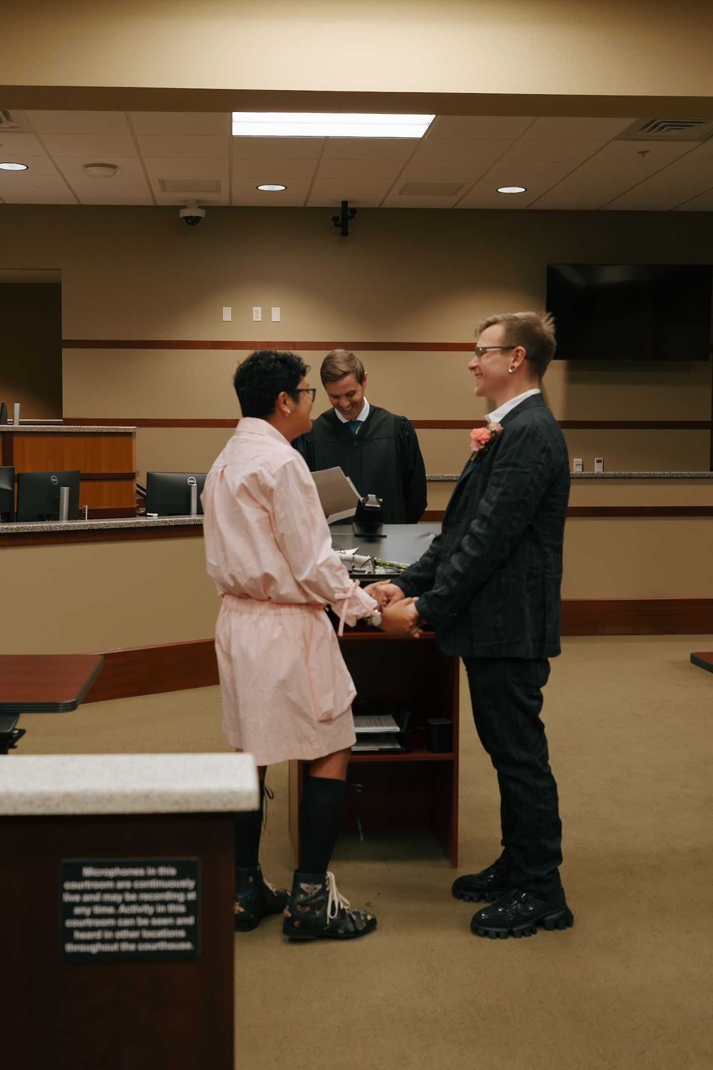 Couple holding hands and exchanging vows before officiant at courthouse wedding ceremony.