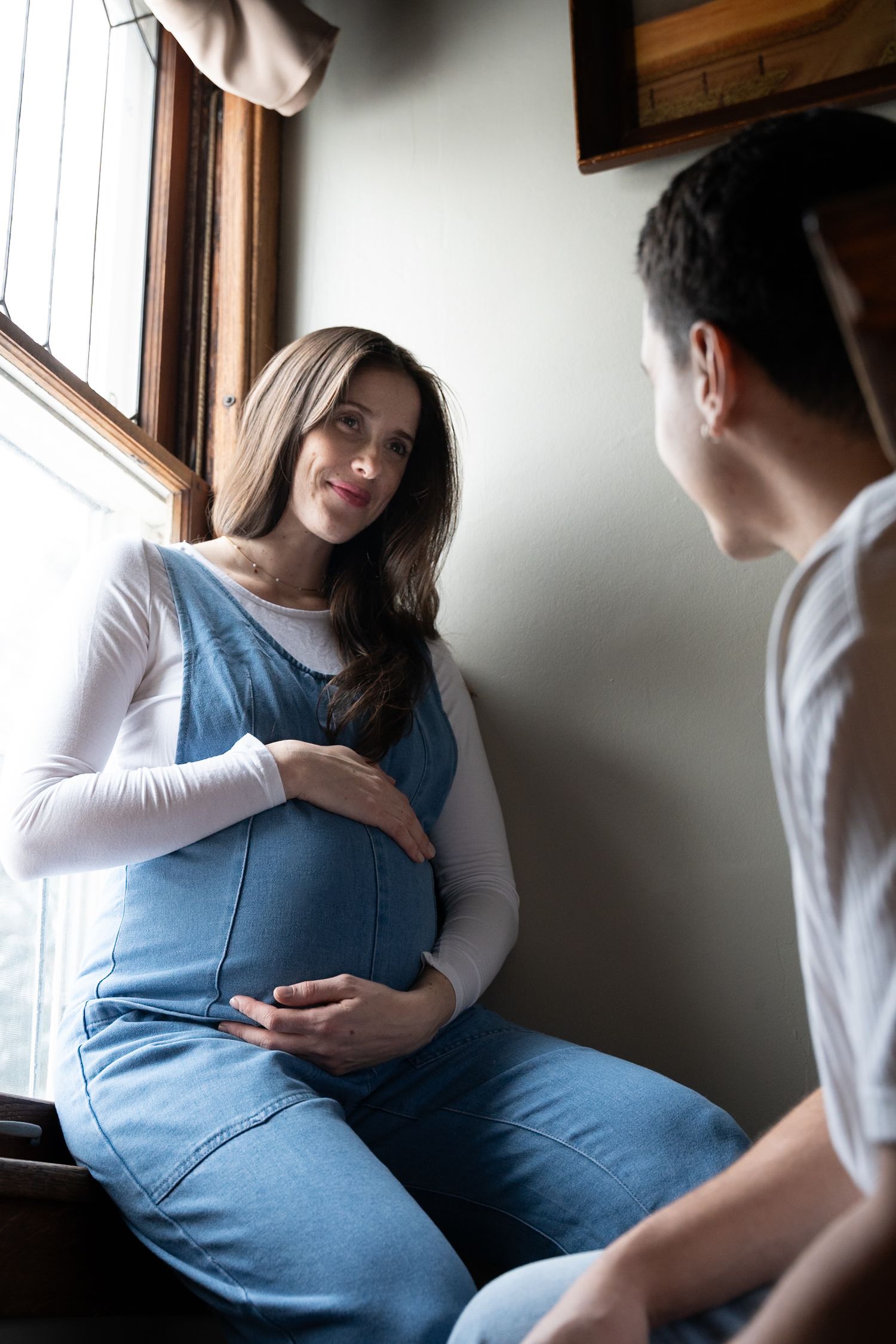 Expectant mother smiling while standing beside her partner during their maternity session.