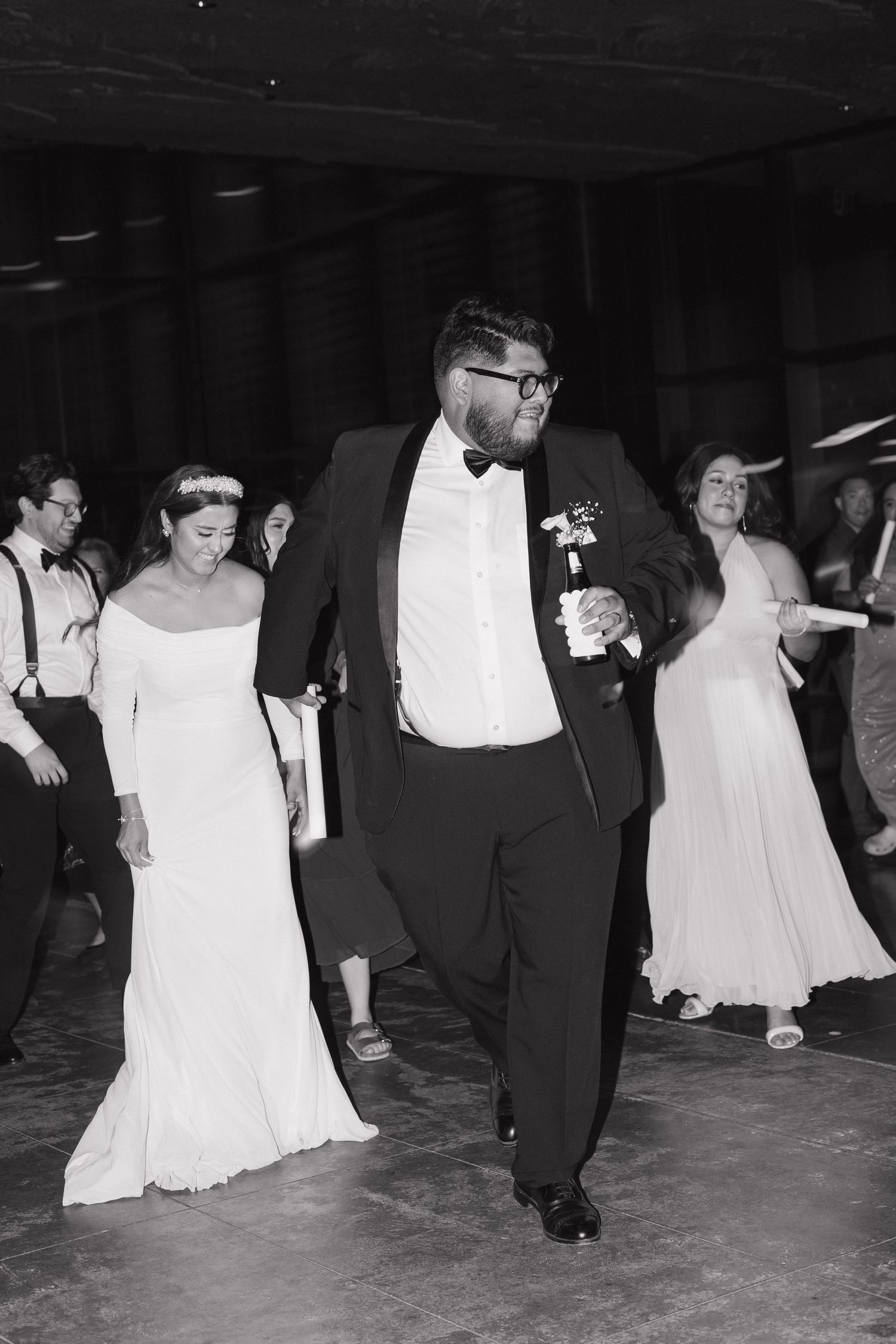 Bride and groom energetically dancing together on wedding reception dance floor in black and white photo.