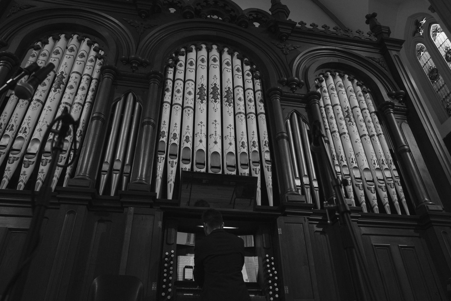 Black and white photo of a grand pipe organ inside a historic Gothic church.