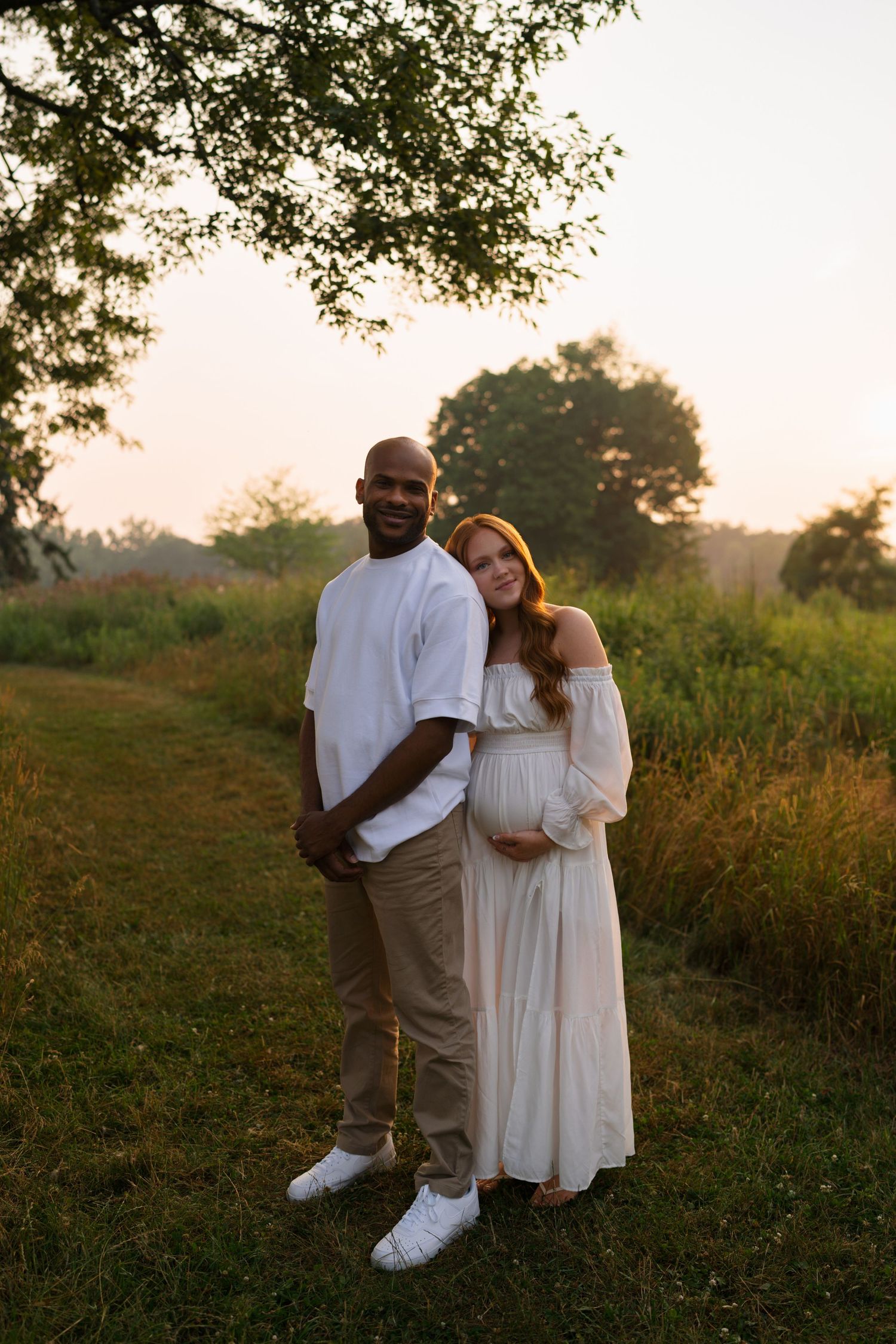 Expectant mother cradling her baby bump during a sunset maternity session.