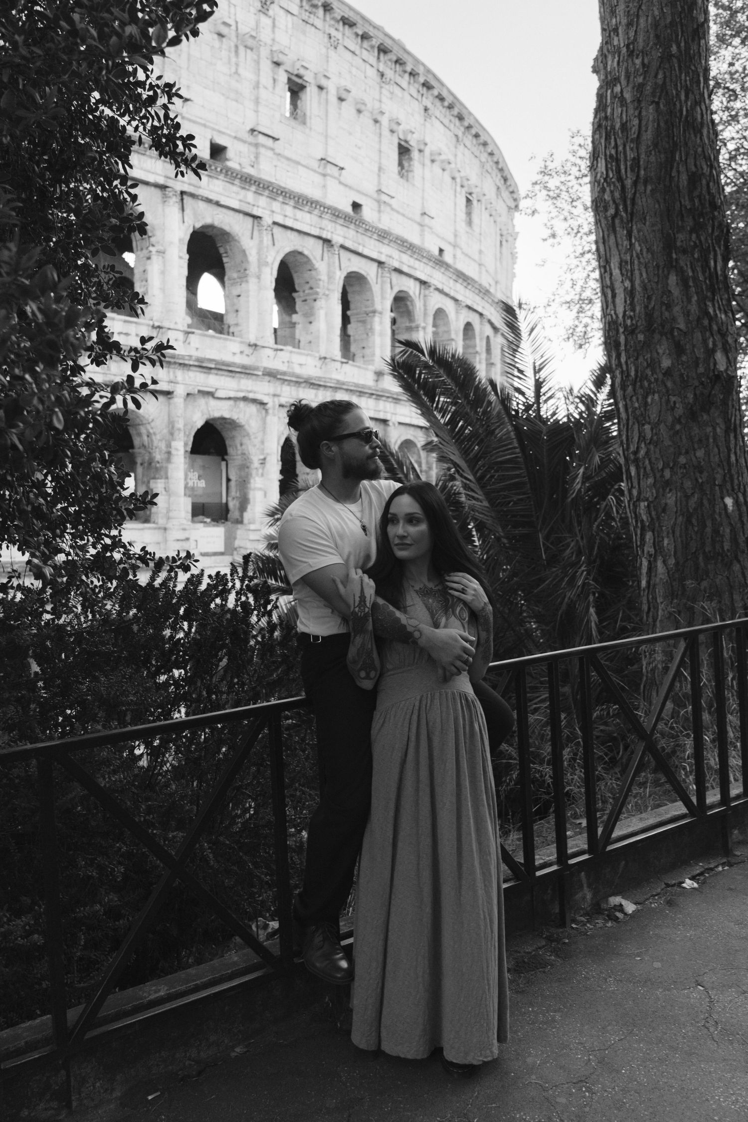 Couple embracing in front of the Colosseum in Rome, Italy, black and white photography.