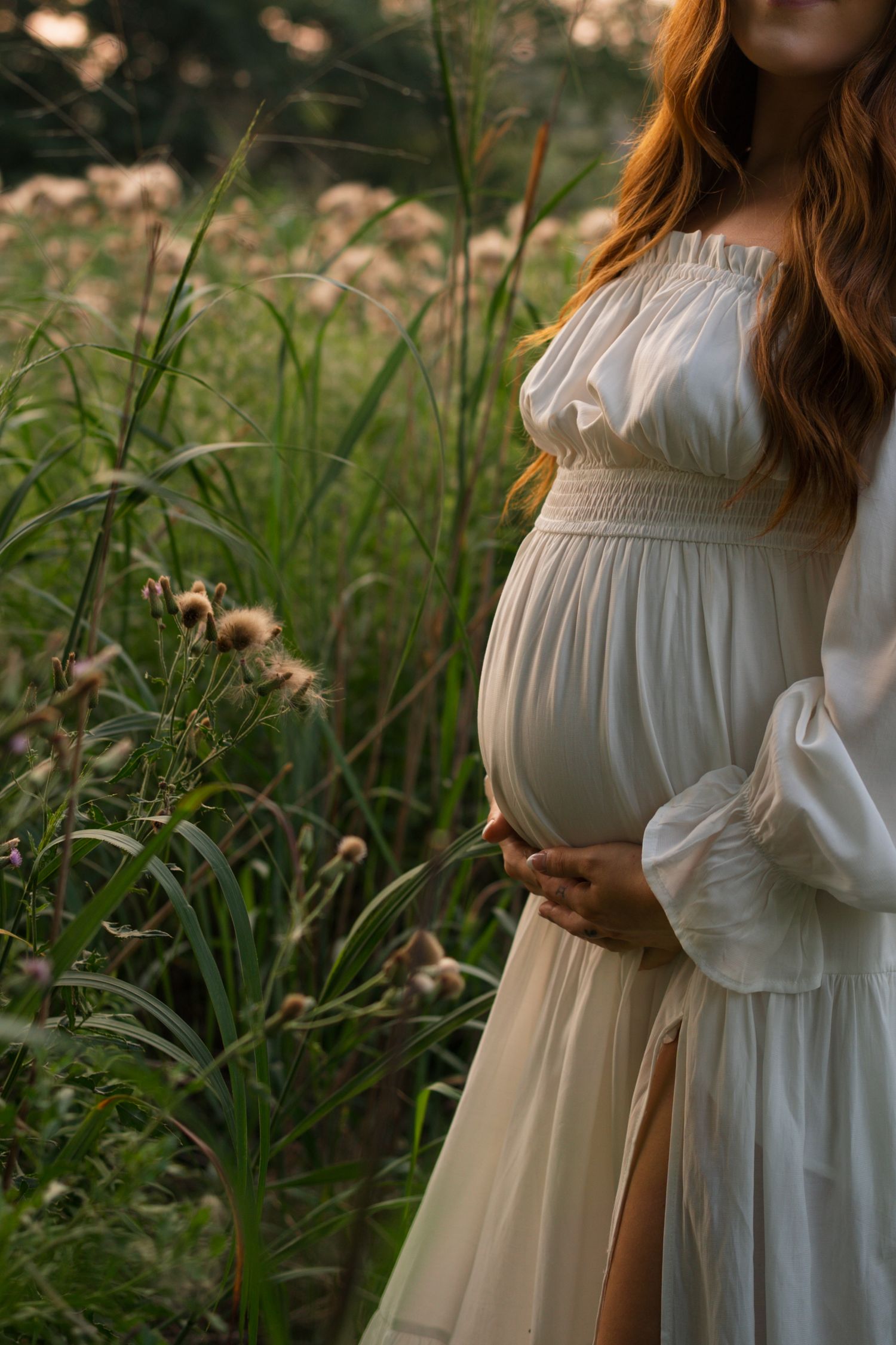 Expectant mother cradling her baby bump among tall prairie grasses at Highlands Prairie.
