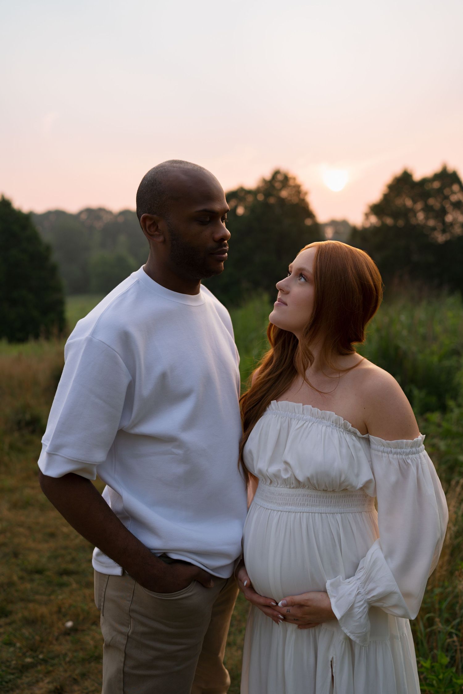 Expectant parents holding hands while walking through Highlands Prairie.
