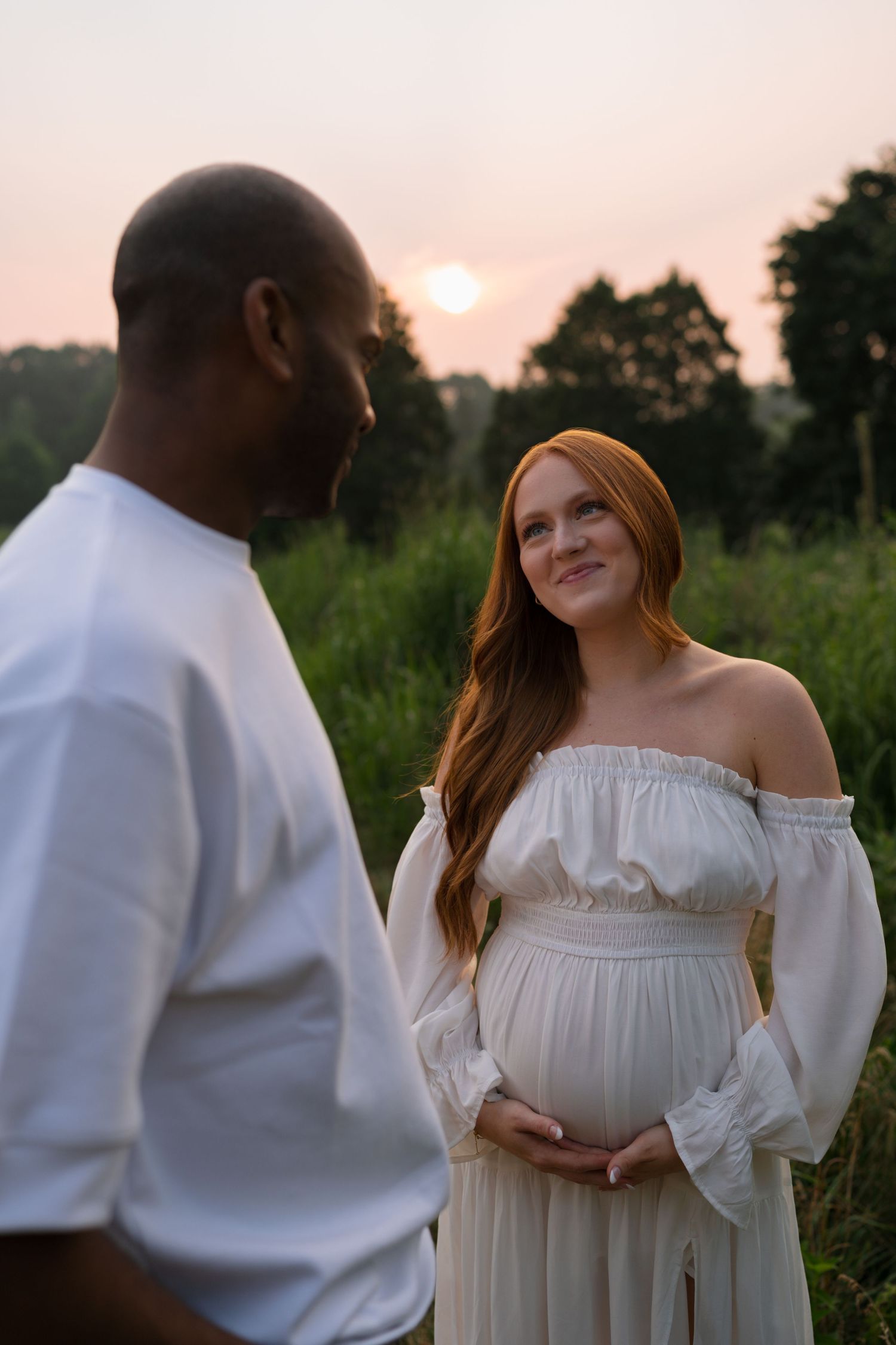 Expectant mother smiling toward her partner during a maternity session at Highlands Prairie.