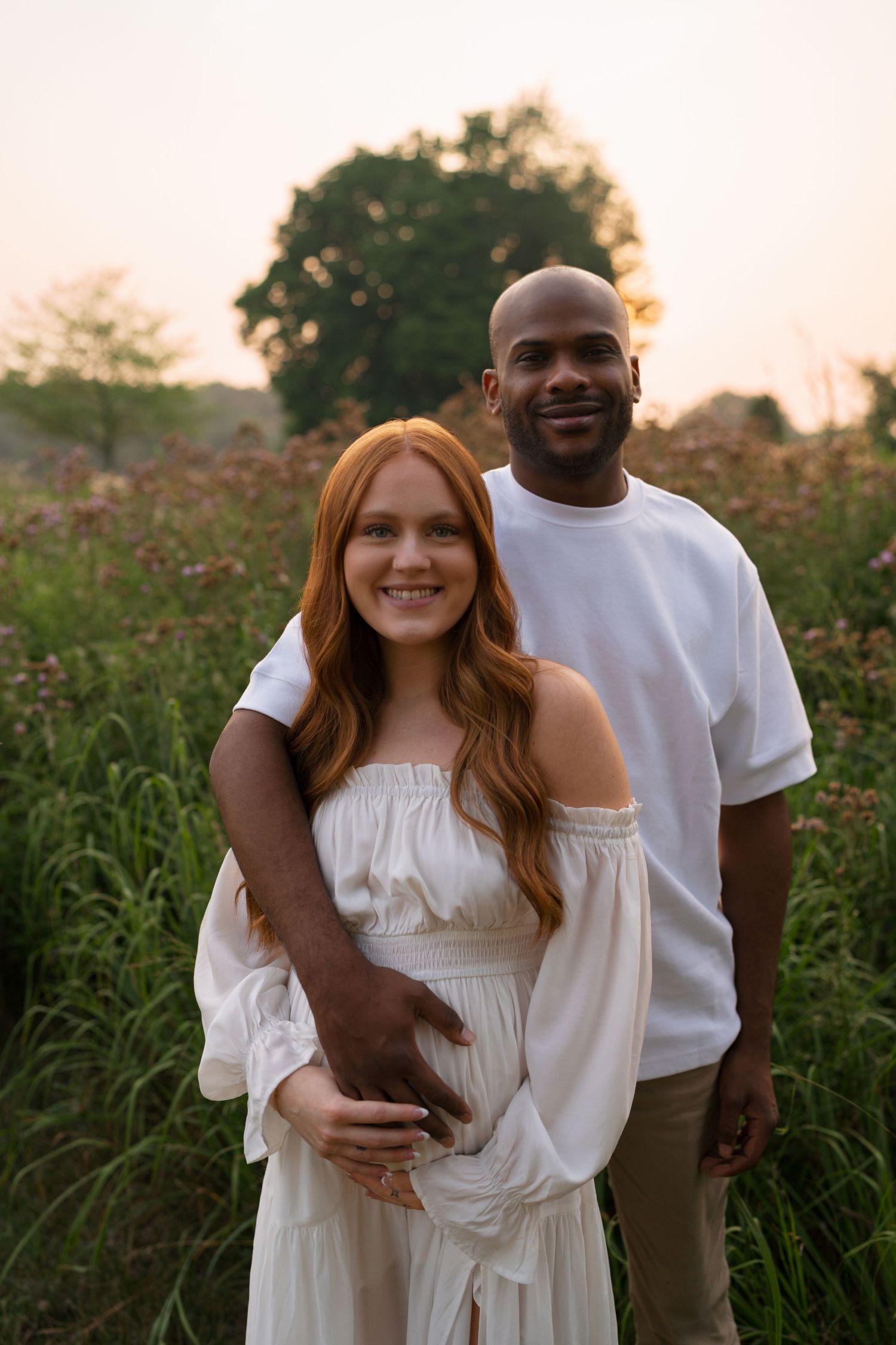 Expectant parents sharing a quiet moment together in the prairie.