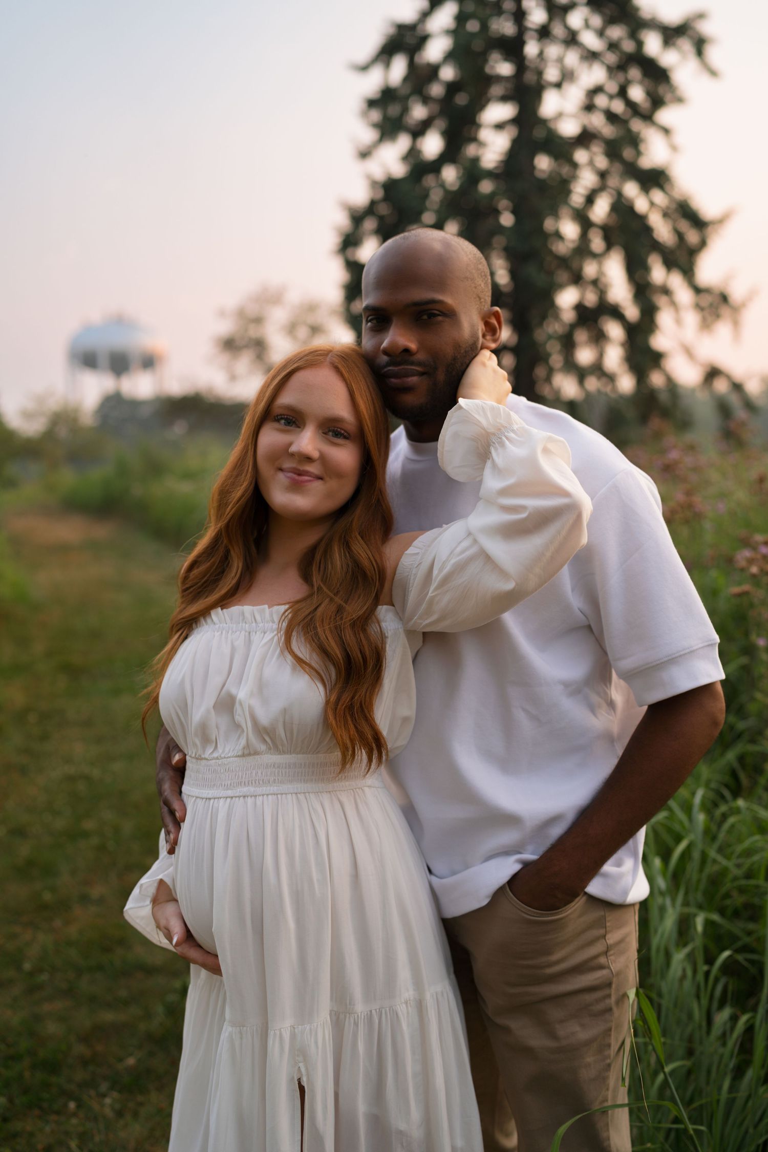 Expectant parents smiling together during a sunset maternity session at Highlands Prairie.