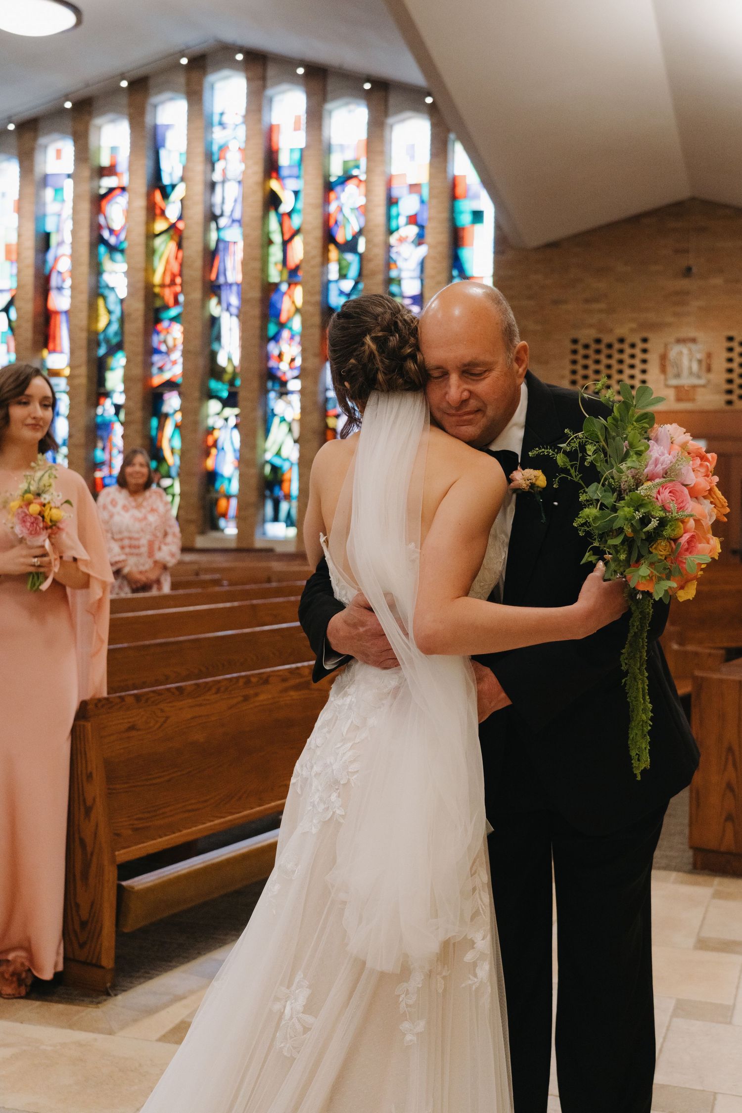 Emotional bride shares a heartfelt hug with her father at the church altar on her wedding day.
