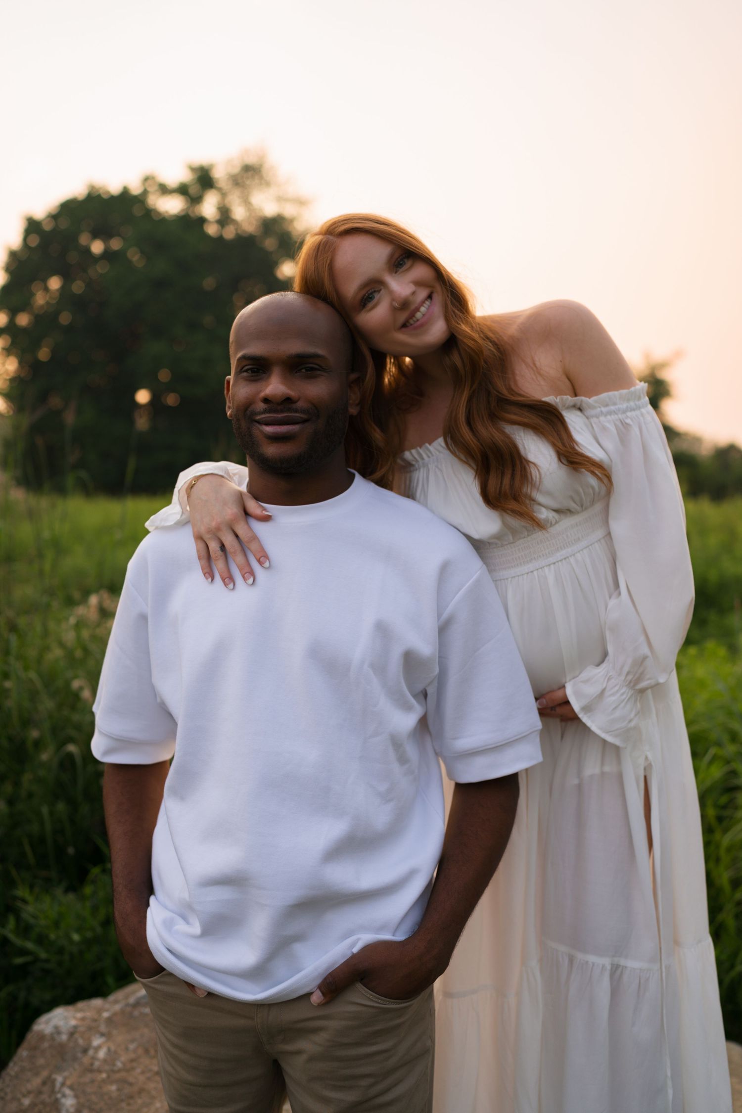 Expectant mother and father sharing a quiet embrace at Highlands Prairie.