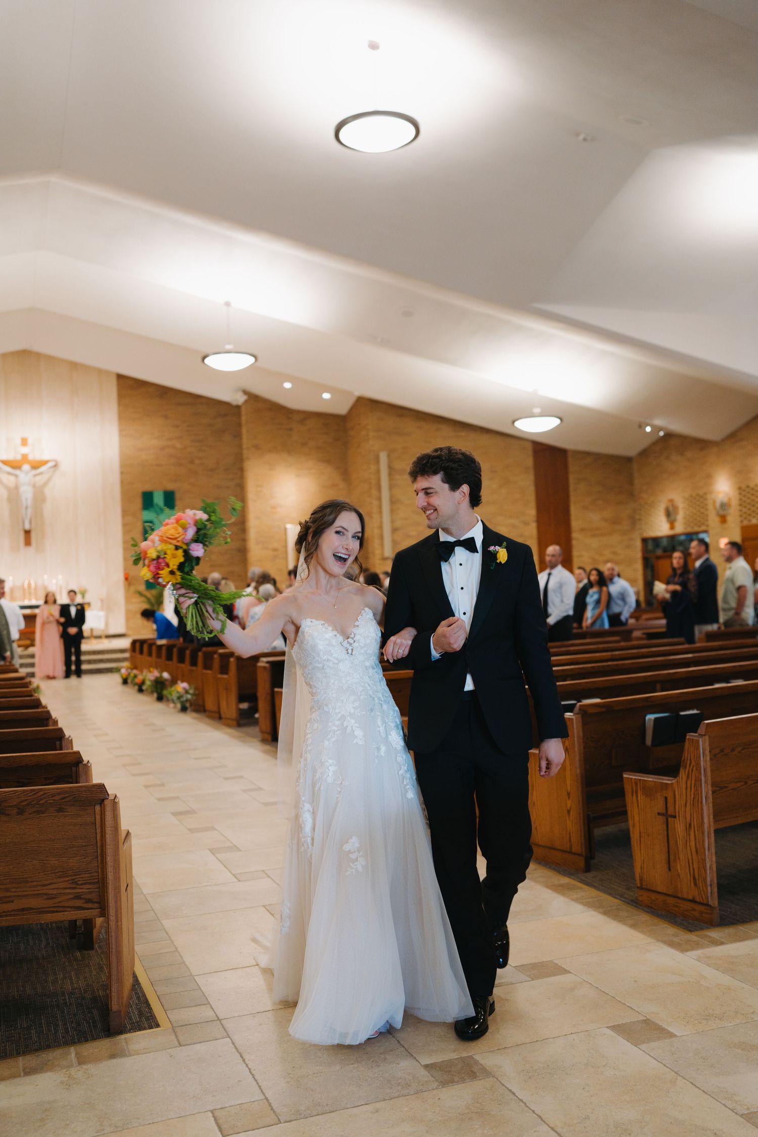 Joyful newlyweds walk back down the church aisle together after their wedding ceremony.