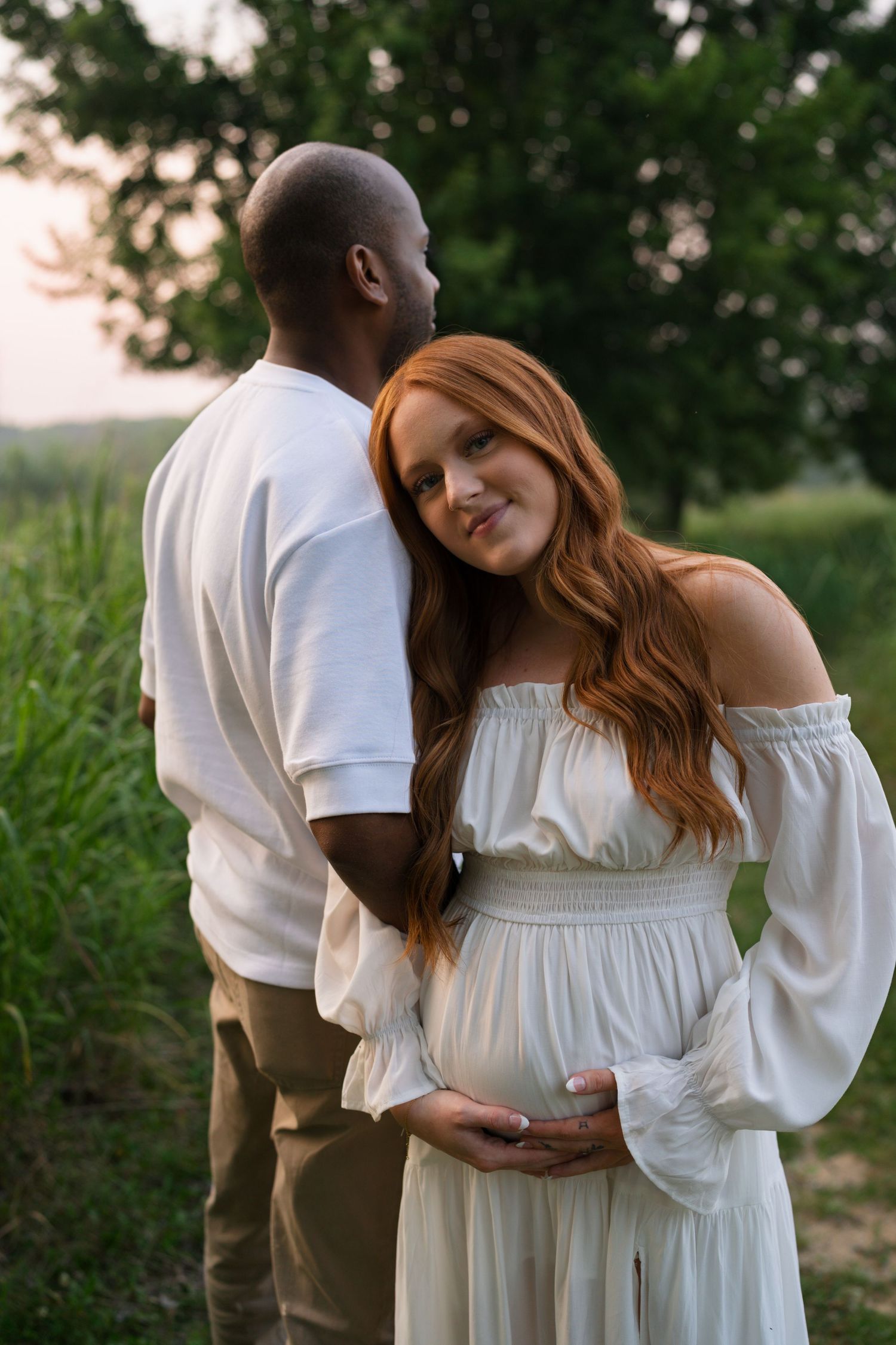 Expectant parents embracing during a golden hour maternity session at Highlands Prairie.
