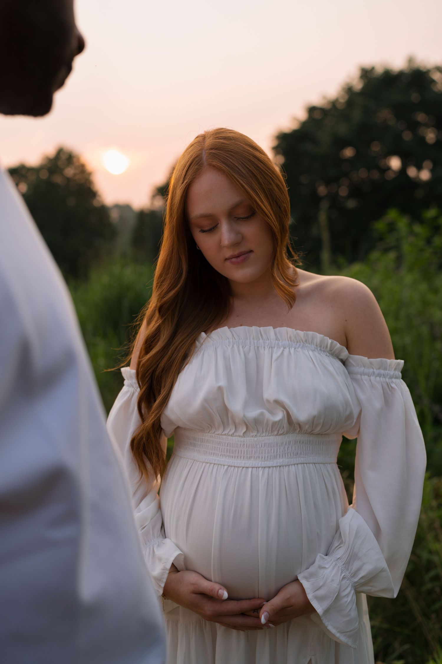 Expectant mother smiling as she walks through Highlands Prairie with her partner.
