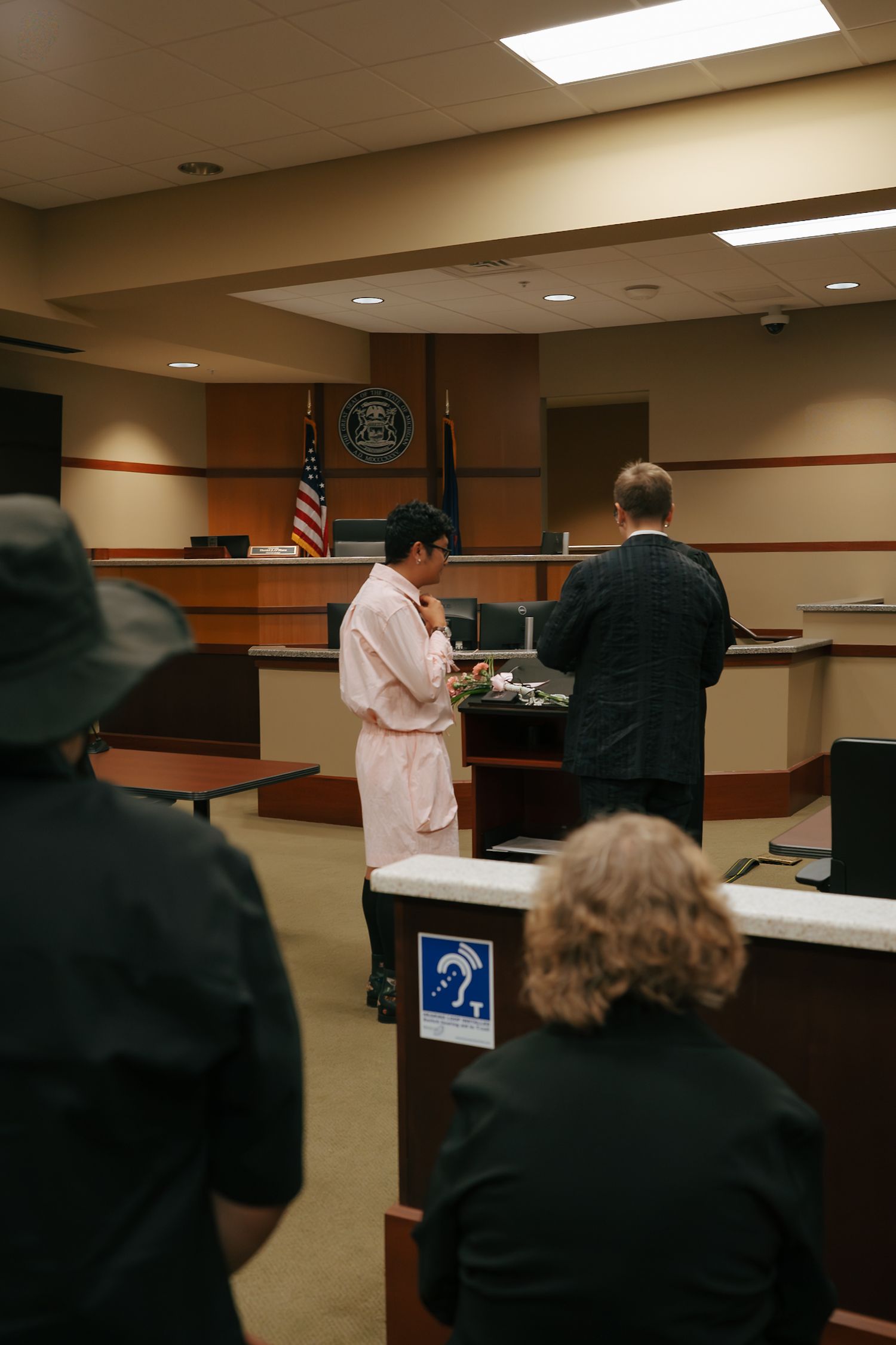 Couple standing before judge during intimate courthouse wedding ceremony with guests watching.