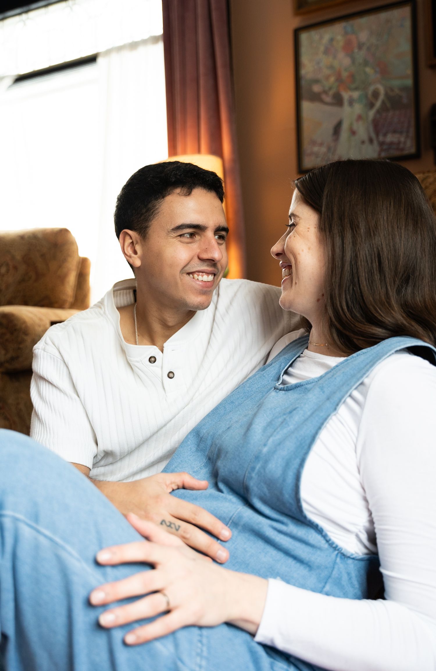 Expectant mother cradling her baby bump in a softly lit bedroom.