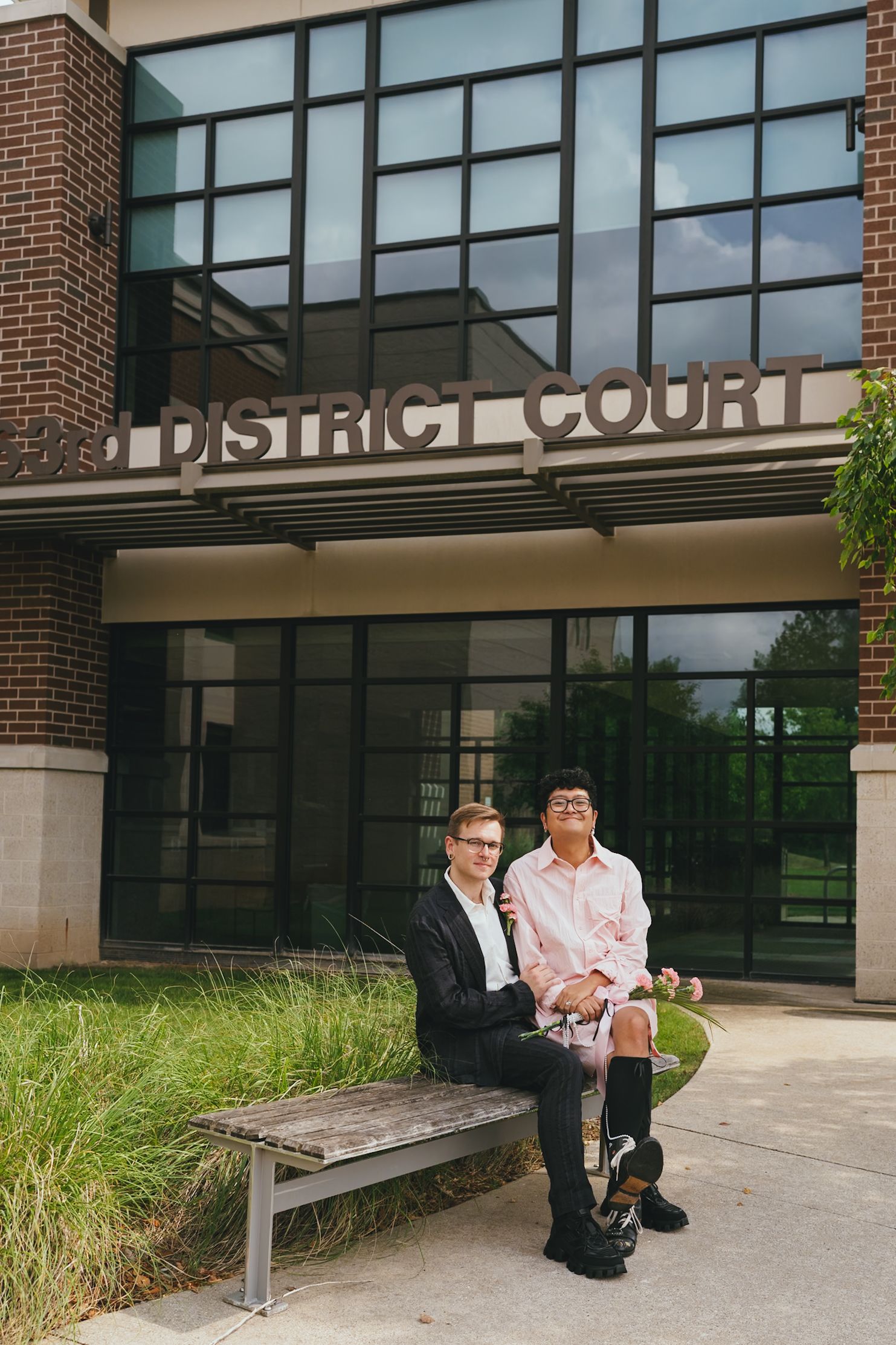 Newlywed couple sitting on bench outside District Court building after courthouse wedding.