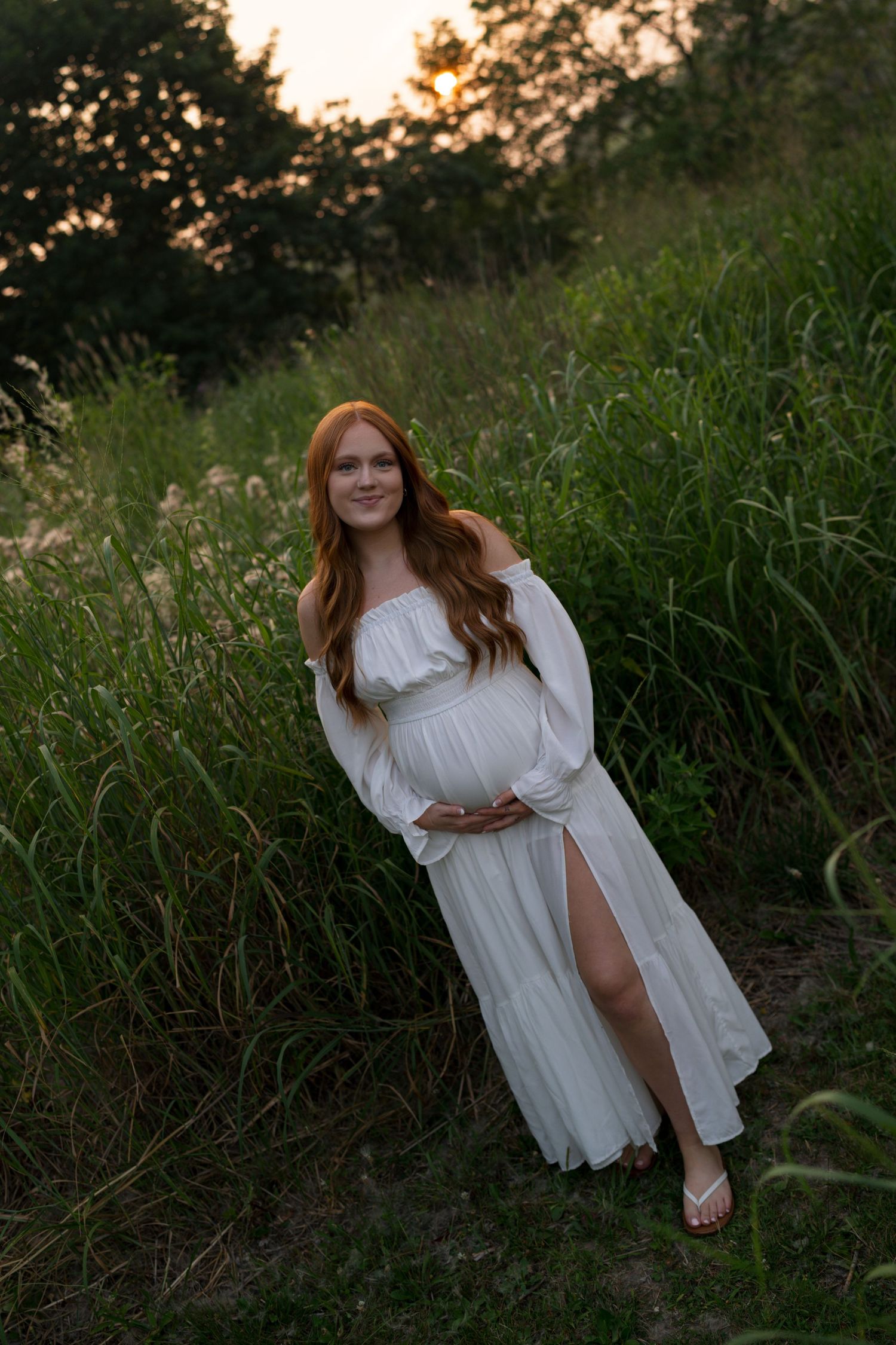 Expectant mother holding her baby bump during a sunset maternity session at Highlands Prairie.