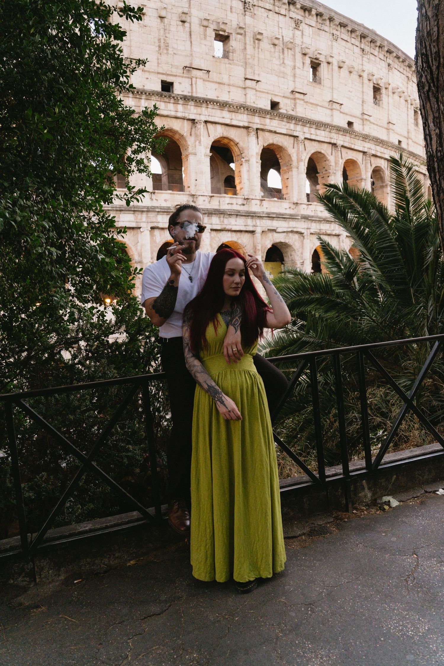 Couple posing in front of the Colosseum in Rome, woman in green dress, man in white shirt.