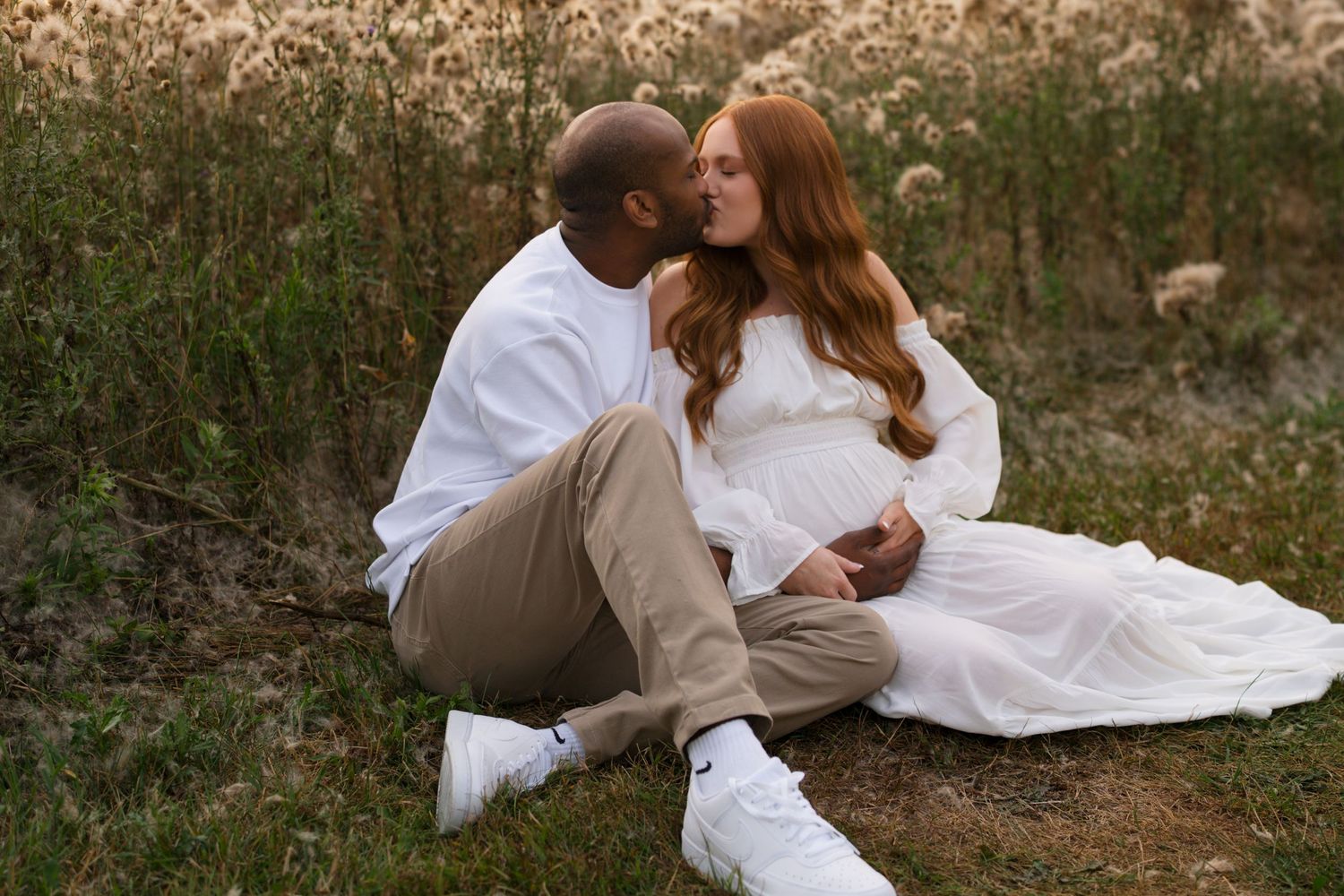 Expectant parents sharing a quiet embrace during their maternity session in the prairie.