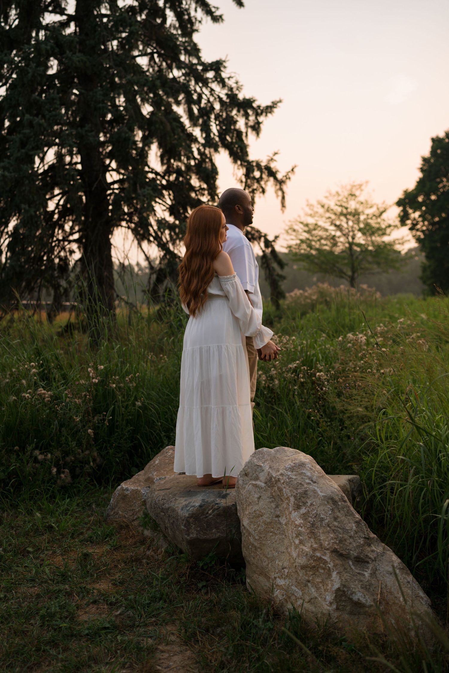Expectant parents standing together during golden hour at Highlands Prairie.