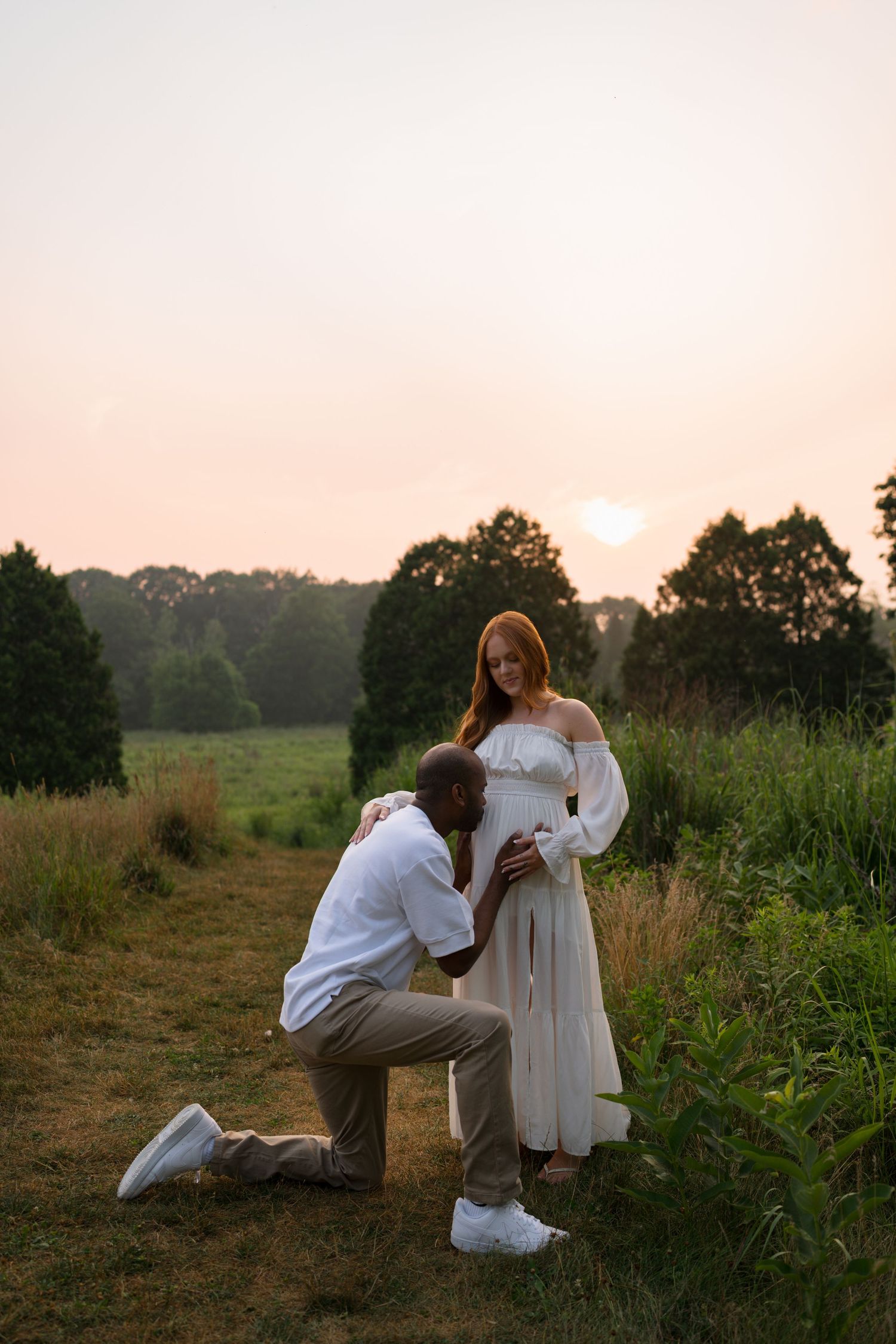 Expectant mother and father embracing in the evening light at Highlands Prairie.