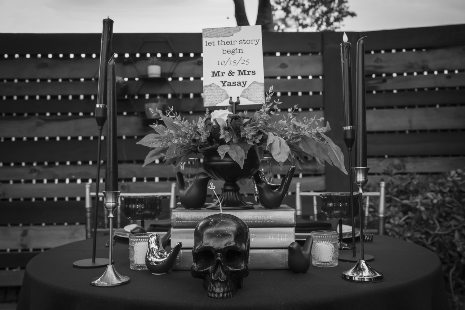 Gothic wedding altar with skull decor, candles, books, and a floral arrangement with Mr & Mrs sign.