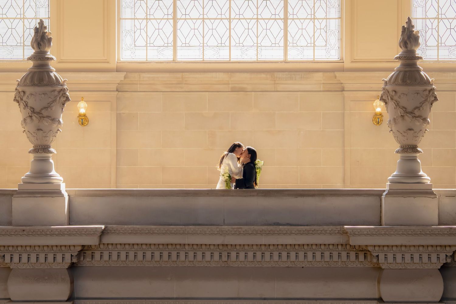Couple shares a romantic kiss on a grand balcony inside a San Francisco City Hall.
